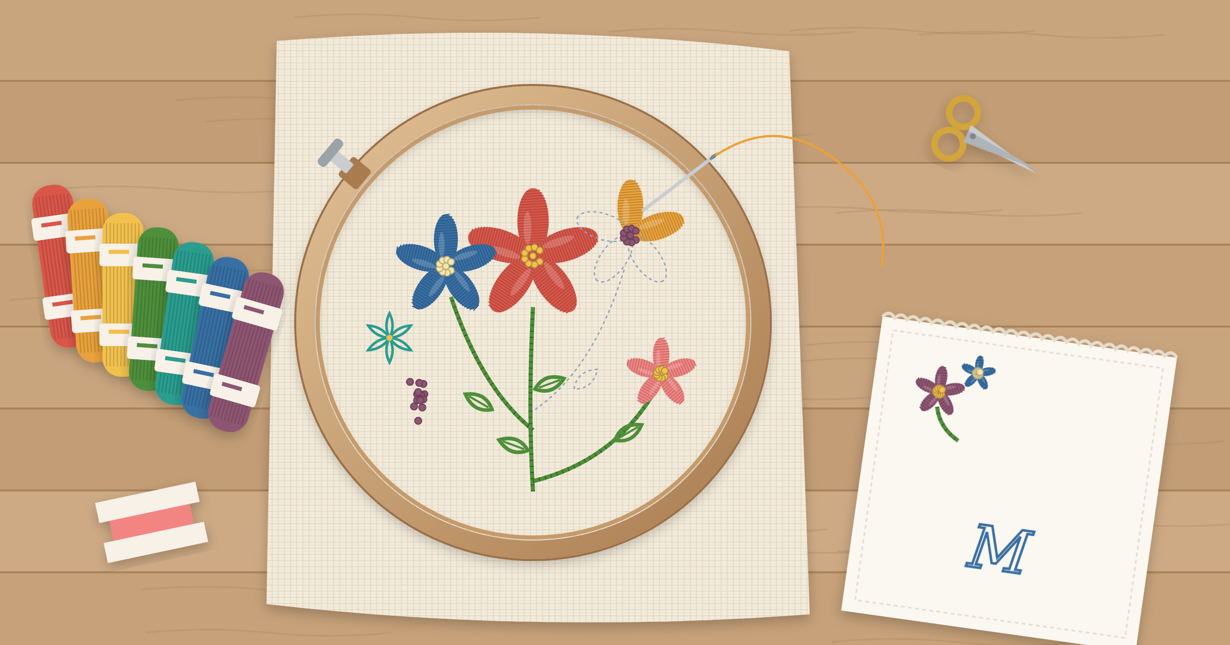 Embroidery hoop with a floral design in progress showing satin stitch, stem stitch, and French knots, surrounded by floss skeins, scissors, and an embroidered monogrammed handkerchief