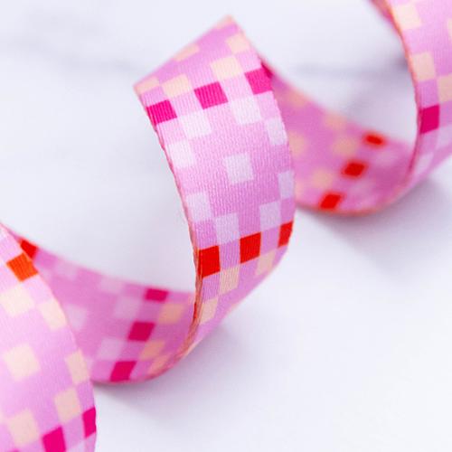 Quadrilateral Macaron 1-inch polyester webbing by Rashida Coleman-Hale featuring a geometric checker pattern in pink, blush, cream, red, and coral.