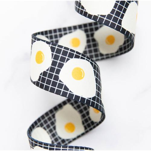 Fried Eggs in Black 1.5-inch polyester webbing by Kimberly Kight featuring white fried eggs with yellow yolks on a black grid background.