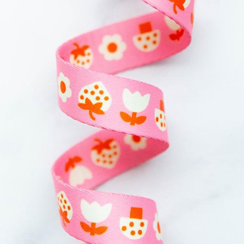Strawbitties in Pink 1-inch polyester webbing by Kimberly Kight featuring cream and orange strawberry-inspired motifs and flowers on a bright pink background.