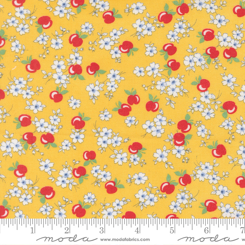 A close-up of 30s Playtime 2025 - Apple Blossom Florals Sunshine Fabric by Linzee McCray for Moda Fabrics, featuring white blossoms and red apples on a warm golden yellow cotton background.