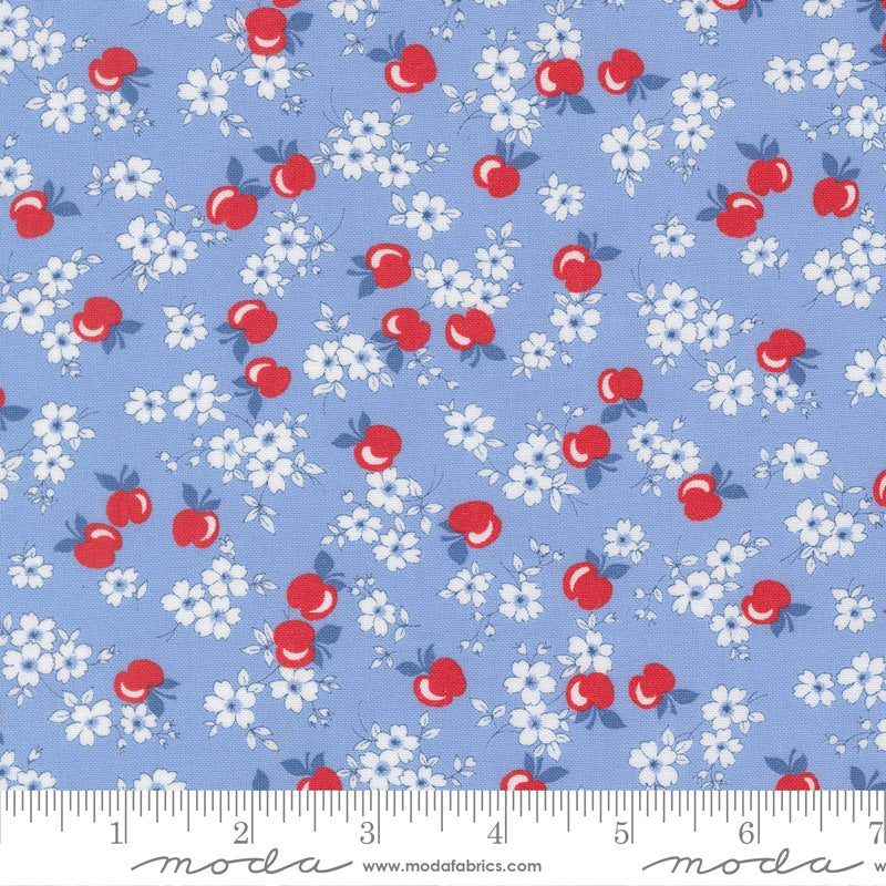A close-up of 30s Playtime 2025 - Apple Blossom Florals Sky Fabric by Linzee McCray for Moda Fabrics, showing red apples and white blossoms on a soft sky-blue cotton background.