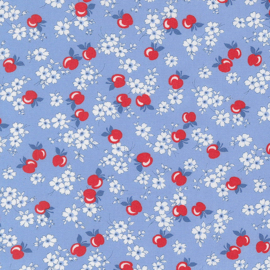 A close-up of 30s Playtime 2025 - Apple Blossom Florals Sky Fabric by Linzee McCray for Moda Fabrics, showing red apples and white blossoms on a soft sky-blue cotton background.