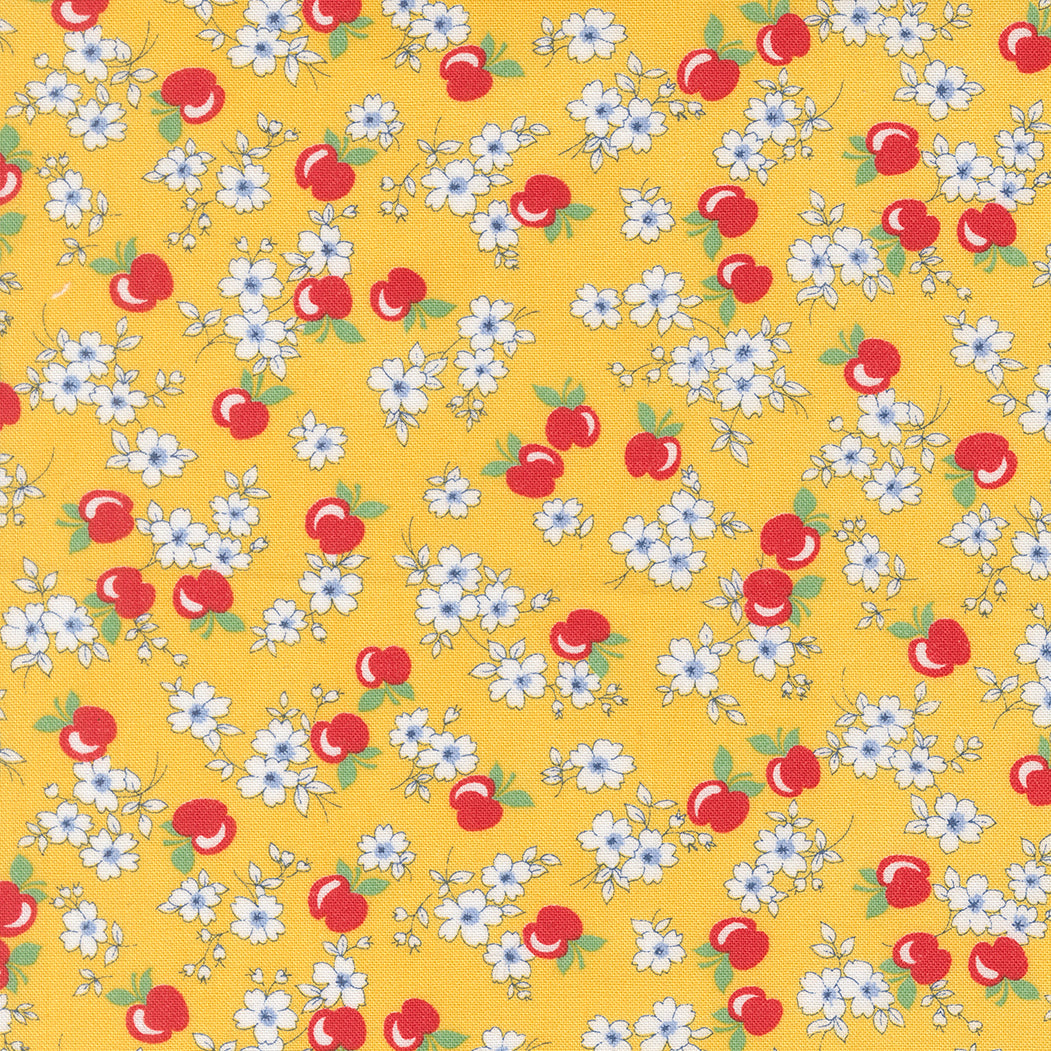 A close-up of 30s Playtime 2025 - Apple Blossom Florals Sunshine Fabric by Linzee McCray for Moda Fabrics, featuring white blossoms and red apples on a warm golden yellow cotton background.