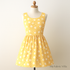 A mannequin displays a sleeveless summer dress made from 30s Playtime 2025 - Perky Posies Sunshine fabric by Linzee McCray for Moda Fabrics, featuring small white flowers on a bright yellow background. The dress is showcased in a softly lit studio with a “My Fabric Villa” watermark in the bottom-right corner for branding.