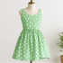 A sleeveless spring sundress displayed on a mannequin, made from 30s Playtime 2025 - Perky Posies Aloe Fabric by Linzee McCray for Moda Fabrics, featuring a soft aloe green background with delicate white floral prints, photographed in a bright studio setting with the “My Fabric Villa” watermark in the bottom right corner.