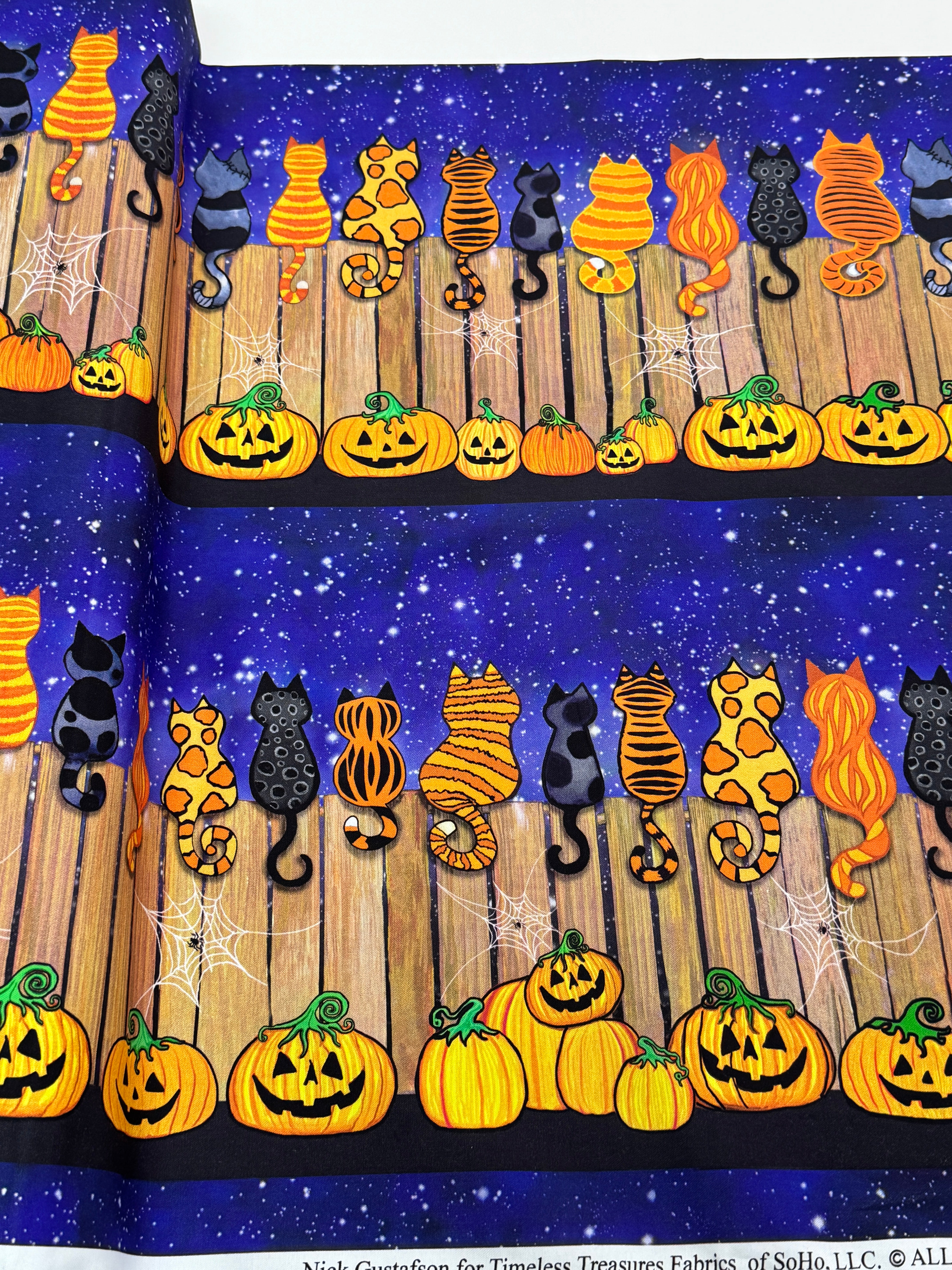 Feline Spooky Cats on Fence cotton fabric by Timeless Treasures featuring colorful Halloween cats, pumpkins, spider webs, and a rustic wooden fence.