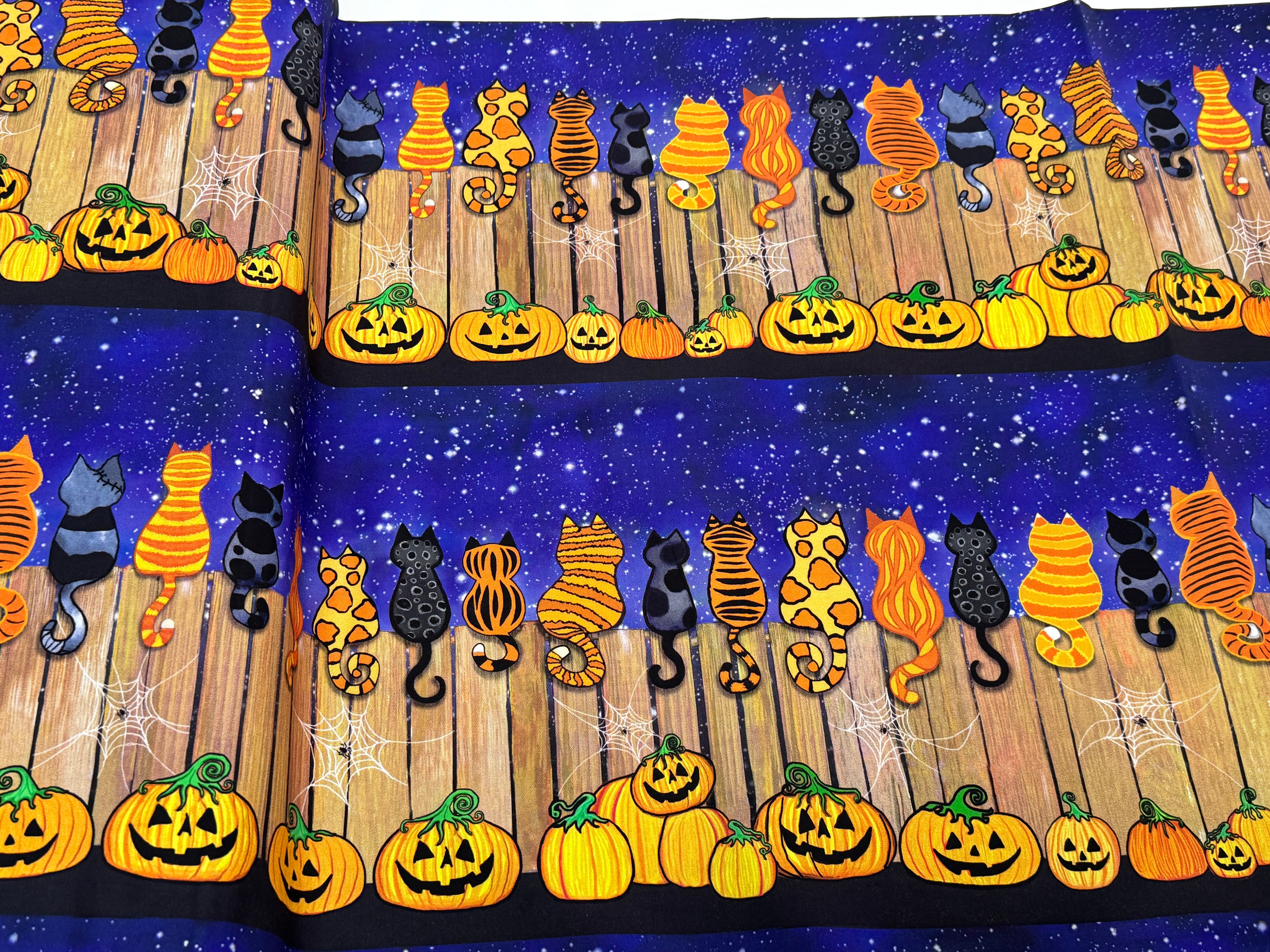 Feline Spooky Cats on Fence cotton fabric by Timeless Treasures featuring colorful Halloween cats, pumpkins, spider webs, and a rustic wooden fence.