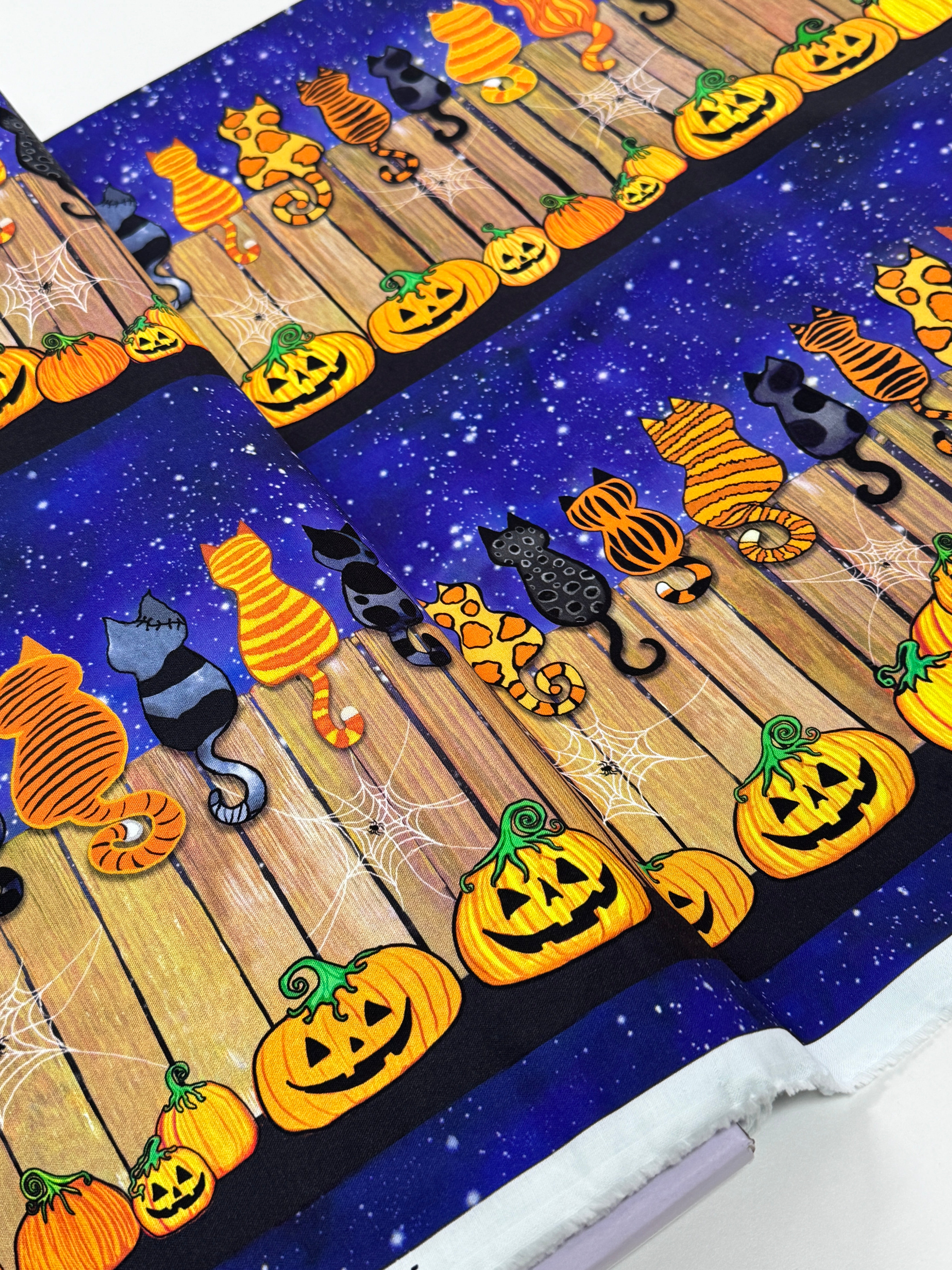 Feline Spooky Cats on Fence cotton fabric by Timeless Treasures featuring colorful Halloween cats, pumpkins, spider webs, and a rustic wooden fence.