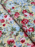 Floral cotton fabric featuring pink roses, blue hydrangeas, and delicate blossoms on a soft butter yellow background from the Simply Chic collection by Anna Stuart for Benartex.