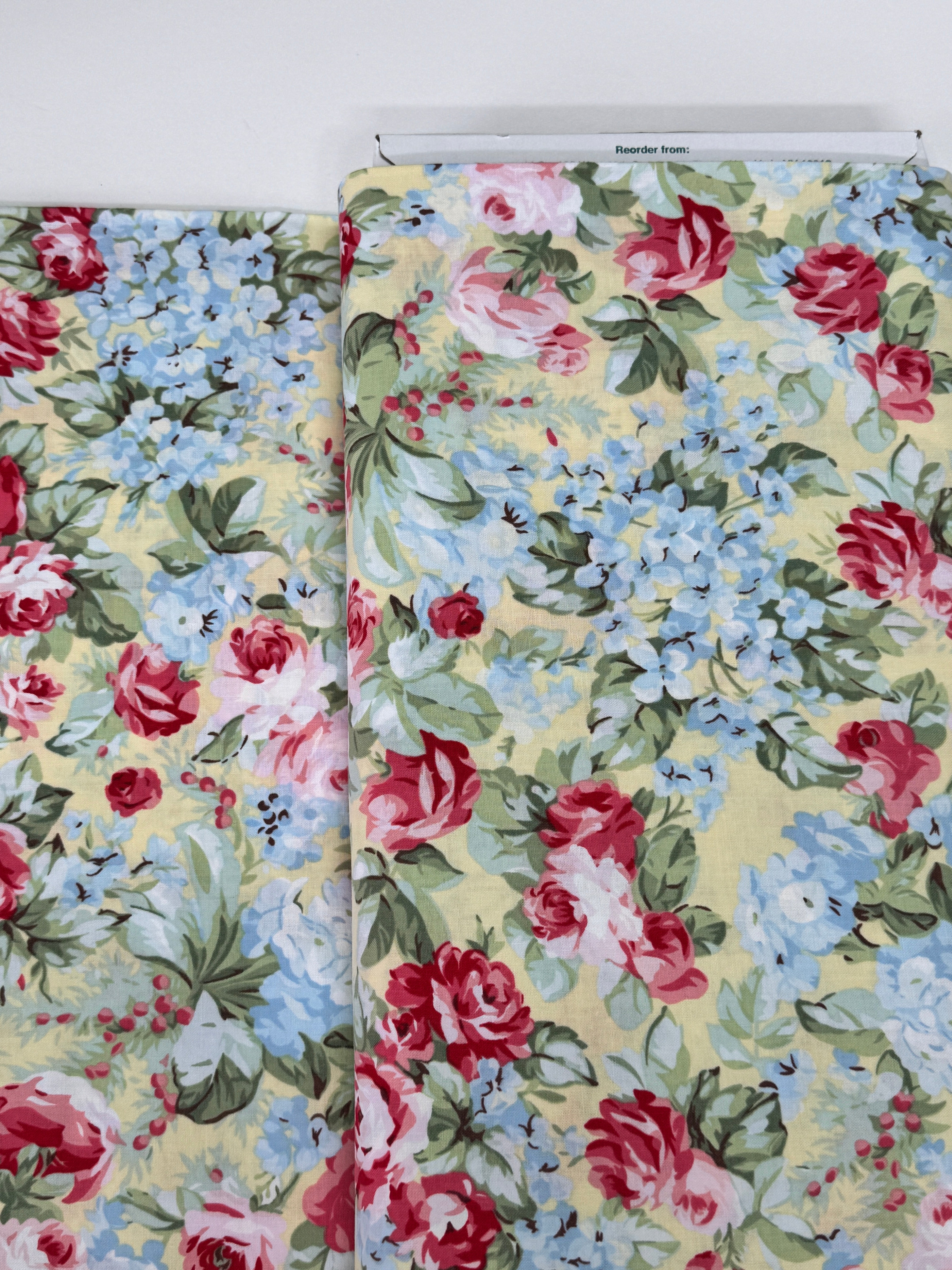 Floral cotton fabric featuring pink roses, blue hydrangeas, and delicate blossoms on a soft butter yellow background from the Simply Chic collection by Anna Stuart for Benartex.