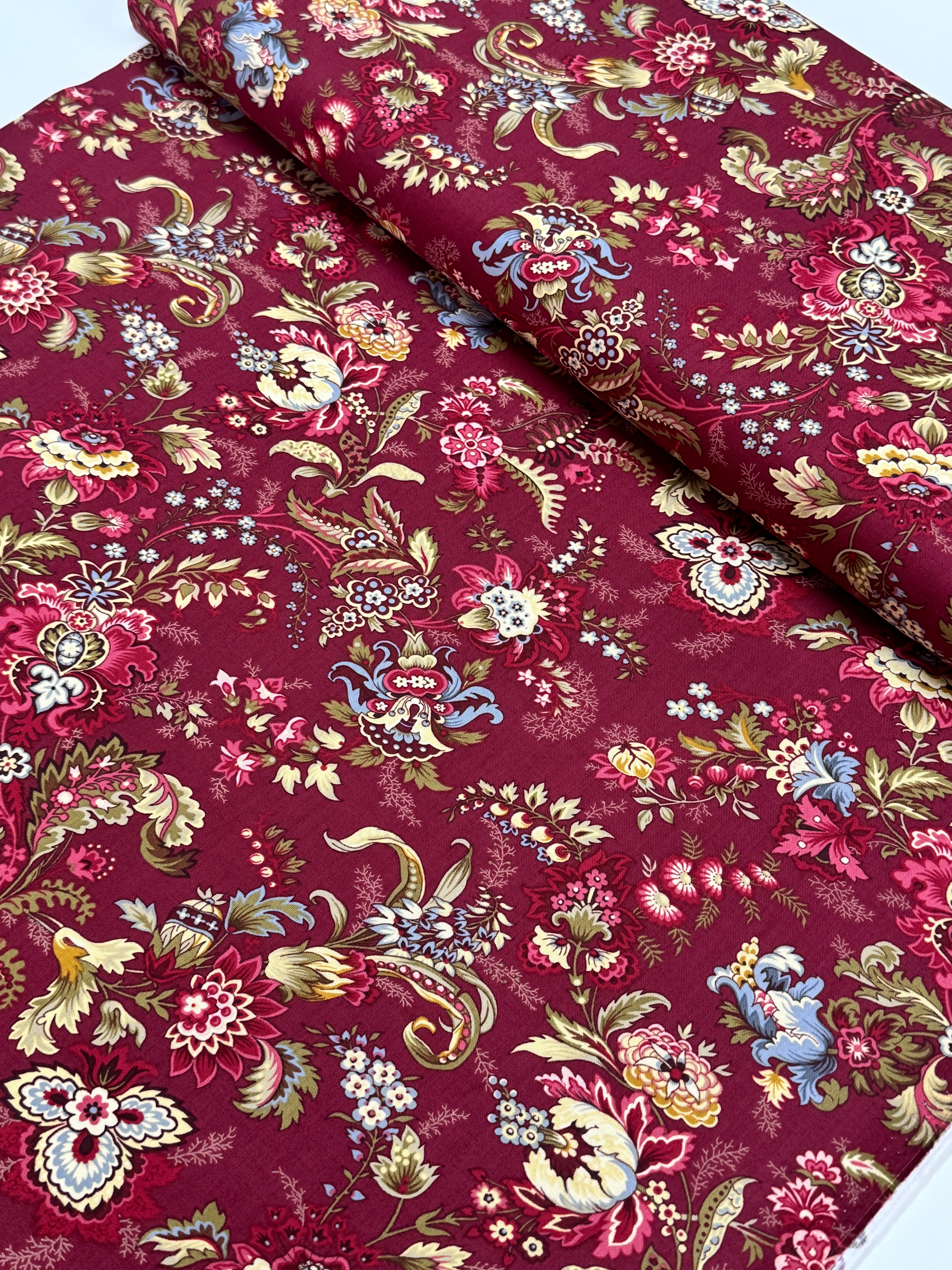 Marseille Red floral cotton fabric by Dover Hill for Benartex featuring ornate botanical flowers and foliage in burgundy, gold, cream, olive green, and blue on a rich red background.