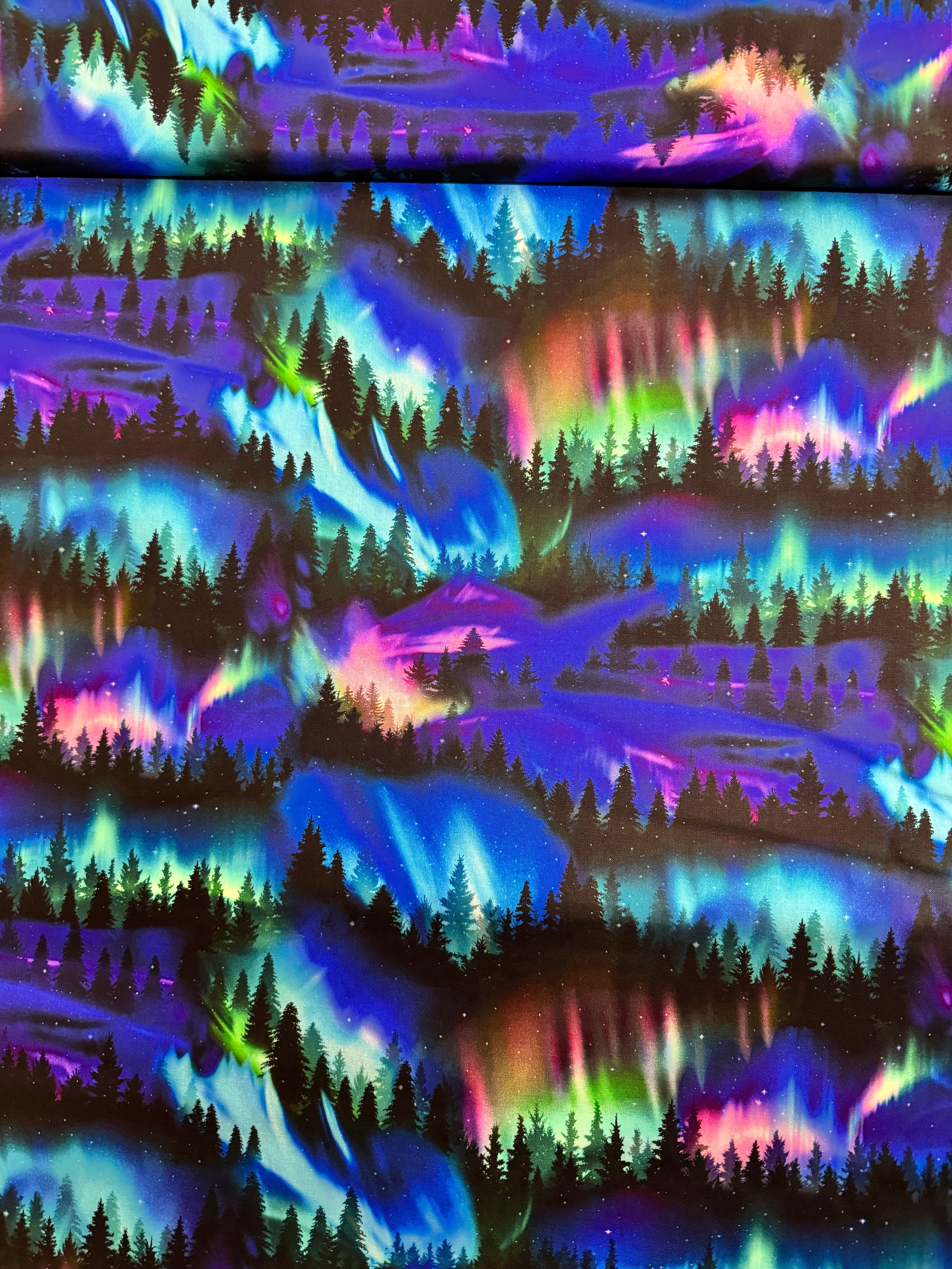 Winter Light - Trees Aurora Borealis fabric by Timeless Treasures, 100% cotton with a scenic forest under colorful aurora sky.