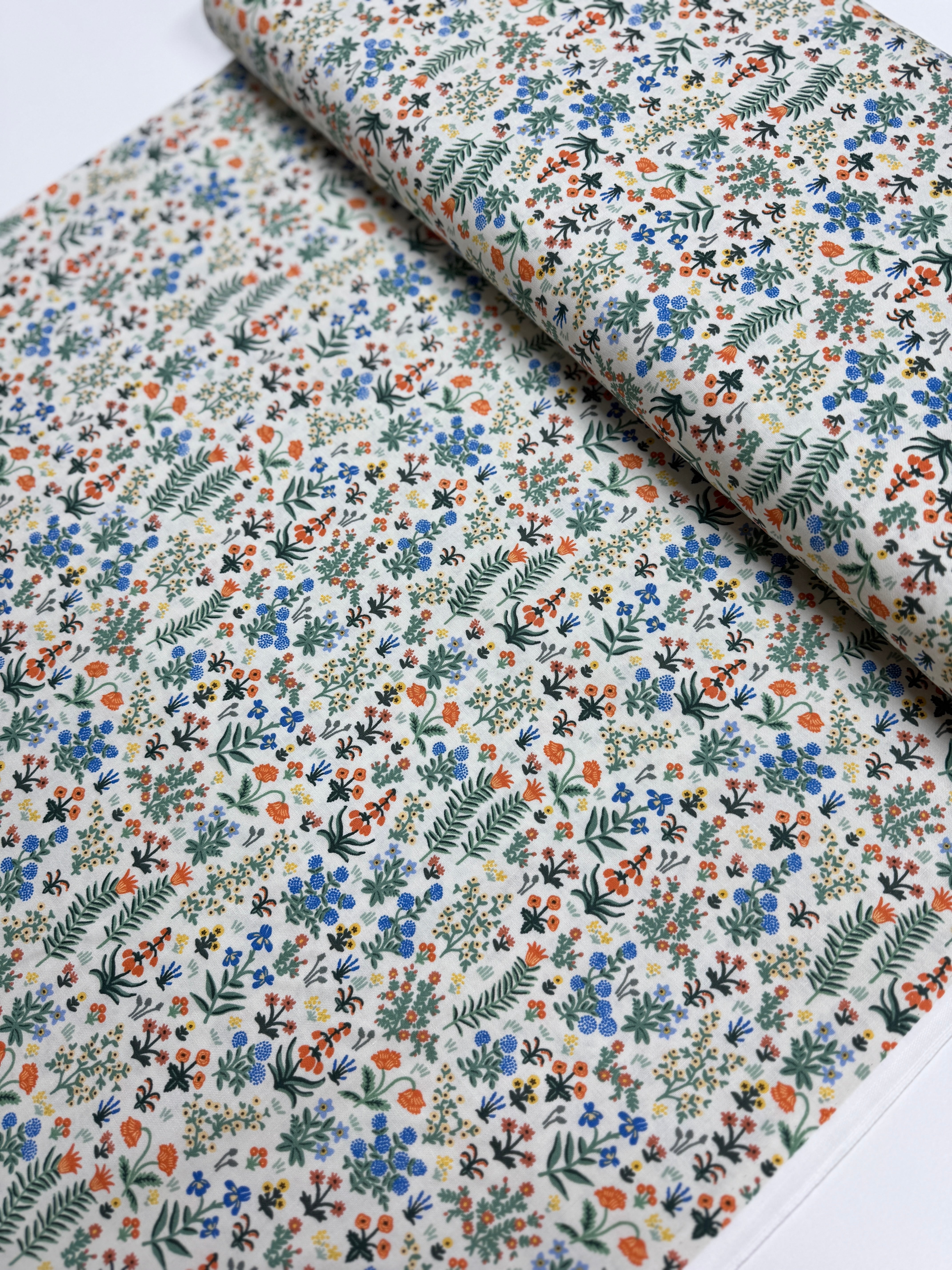 Camont Menagerie Garden Cream quilting cotton by Rifle Paper Co. for Cotton + Steel has flowers and fern like leaves on a cream background.