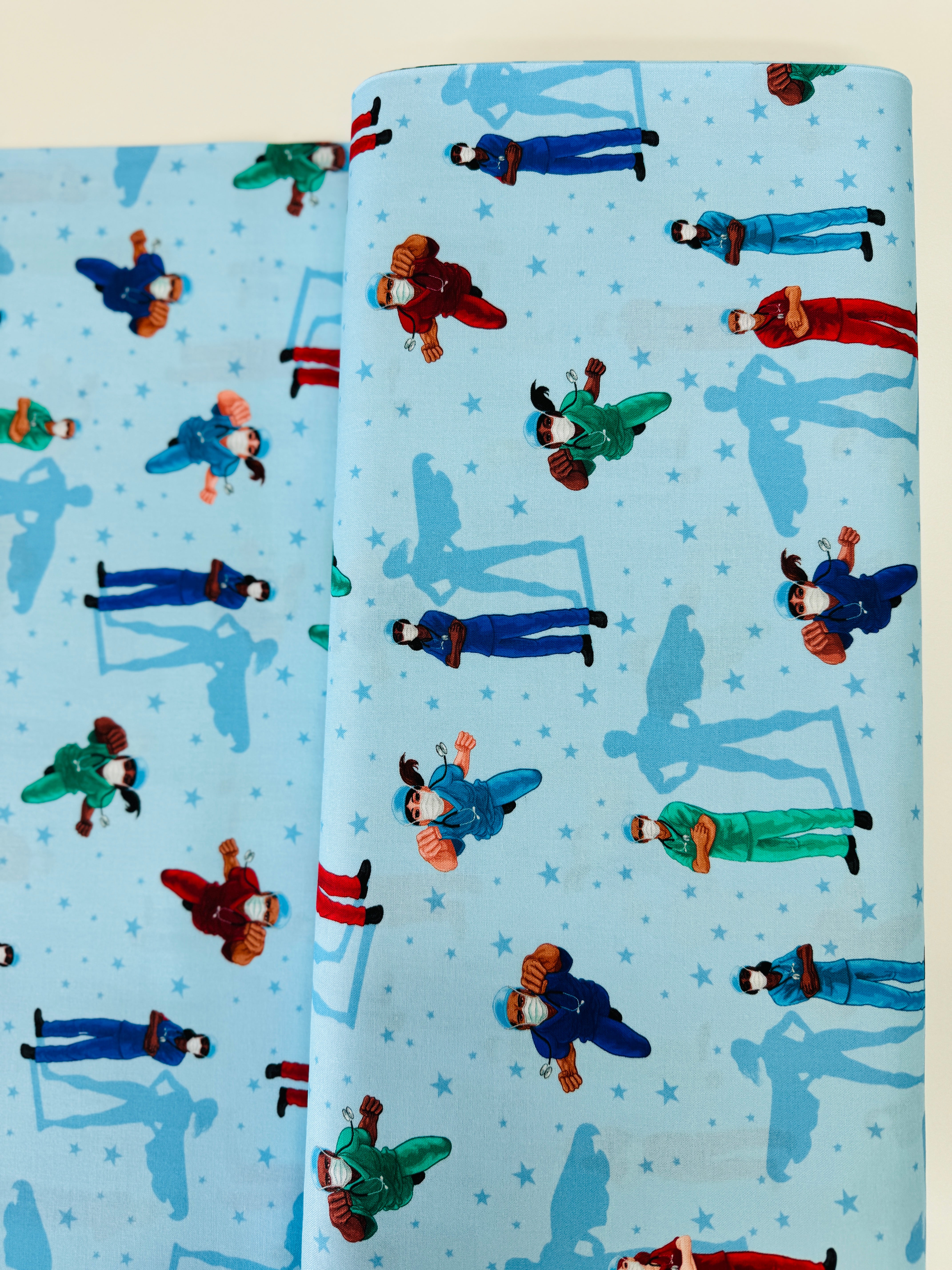 Frontline Heroes on Blue quilting cotton by Robert Kaufman – medical doctors and nurses motif on blue background, 43″ wide