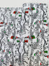 White cotton fabric with skeleton dinosaur T‑Rex prints wearing Santa hats and holding presents