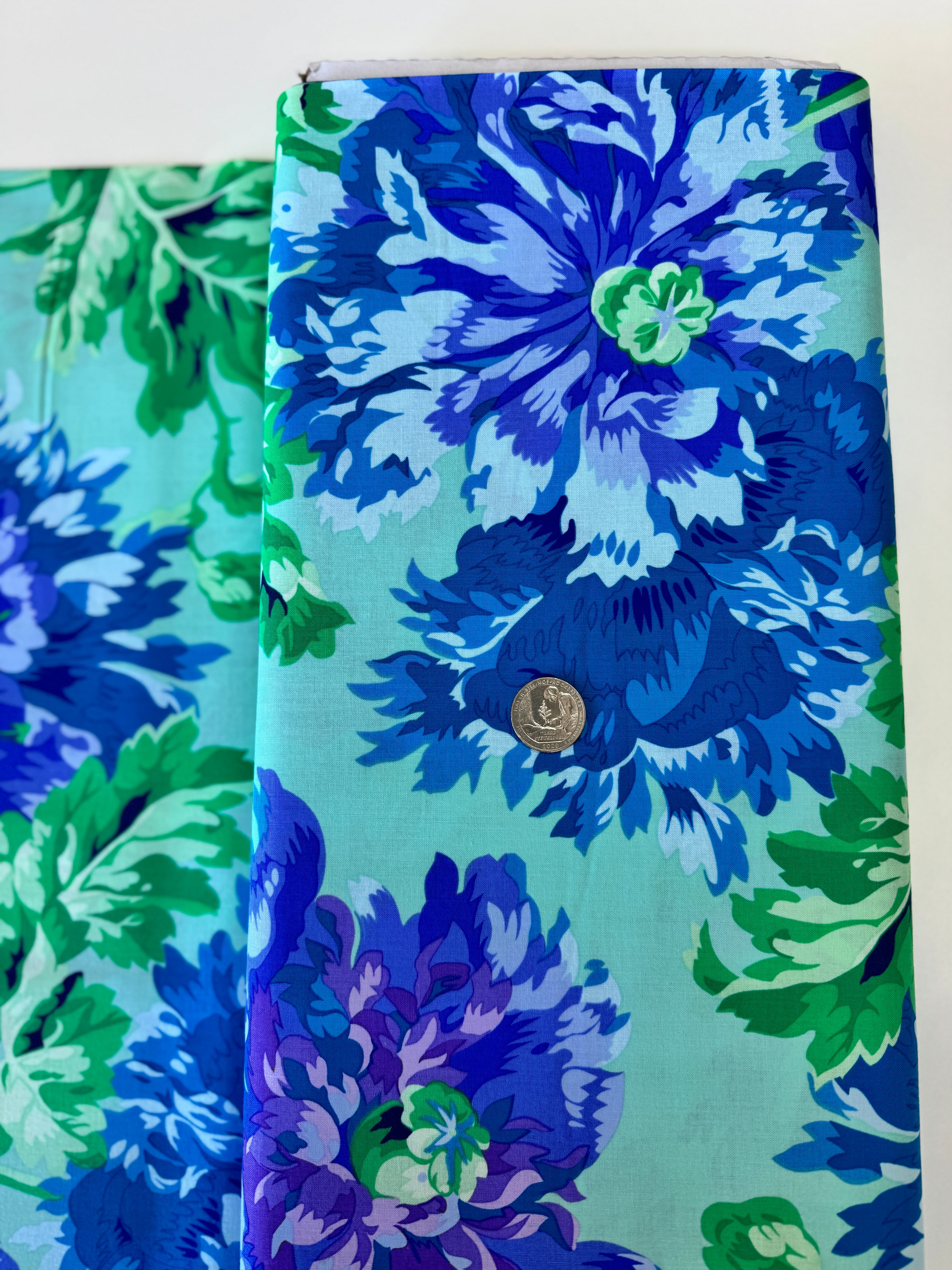 Kaffe Fassett Collective Garden Party Celadon fabric by Philip Jacobs for Free Spirit Fabrics featuring large blue and purple floral blooms with green leaves on a celadon background.