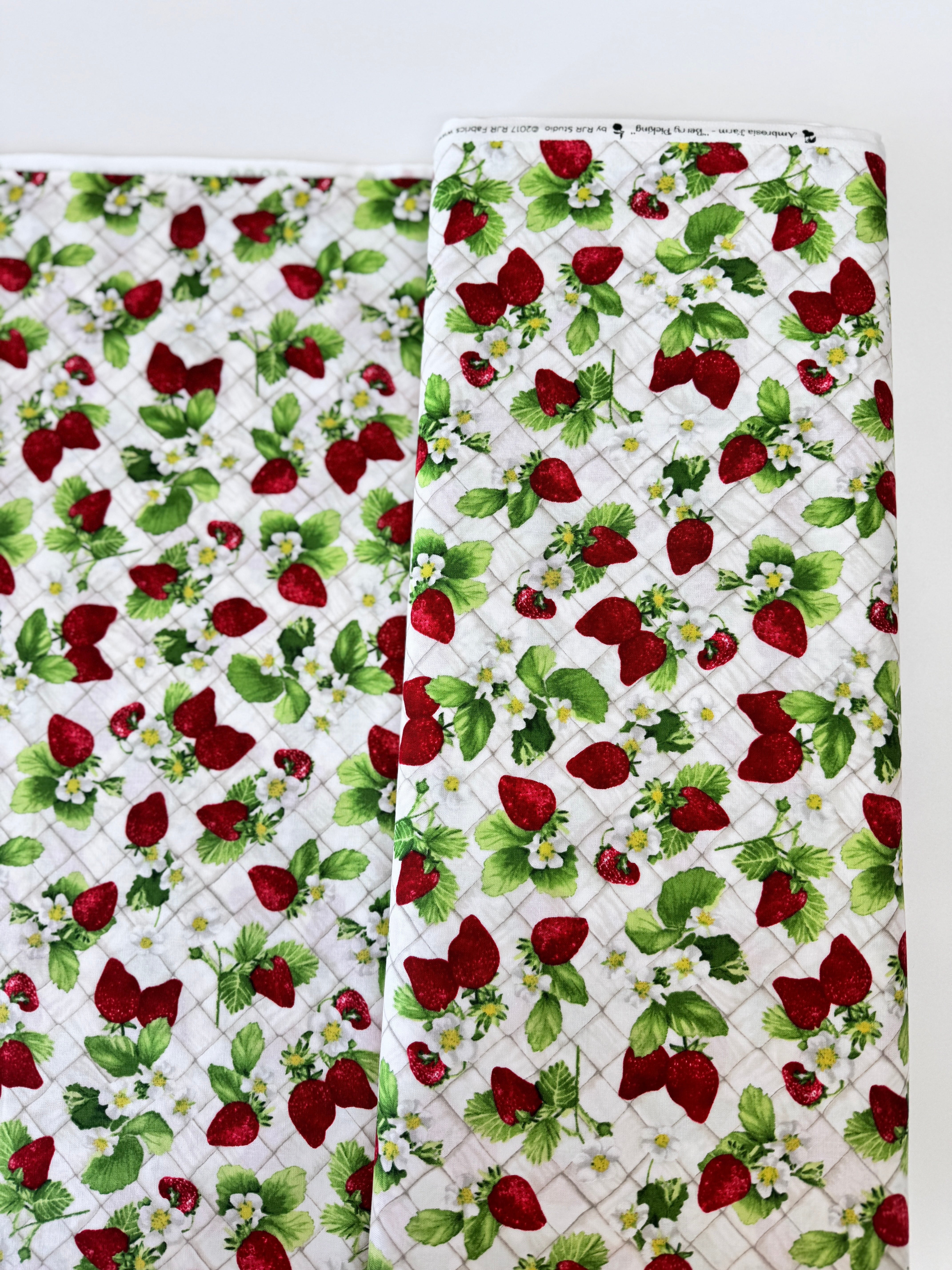 Ambrosia Farm Berry Picking Natural fabric by RJR Studio for RJR Fabrics featuring red strawberries, green leaves, and white flowers on a cream grid background.