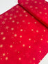 A vibrant red fabric from the Ombre Flurries Metallic collection by V and Co. for Moda Fabrics, featuring shimmering gold metallic snowflakes scattered across the surface.