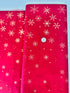 A vibrant red fabric from the Ombre Flurries Metallic collection by V and Co. for Moda Fabrics, featuring shimmering gold metallic snowflakes scattered across the surface.