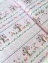 A pastel pink cotton fabric featuring rows of playful deer, white bunnies, trees, and flowers in a stripe pattern - Storybook Forest - Bunnies & Deer Stripe by Timeless Treasures.