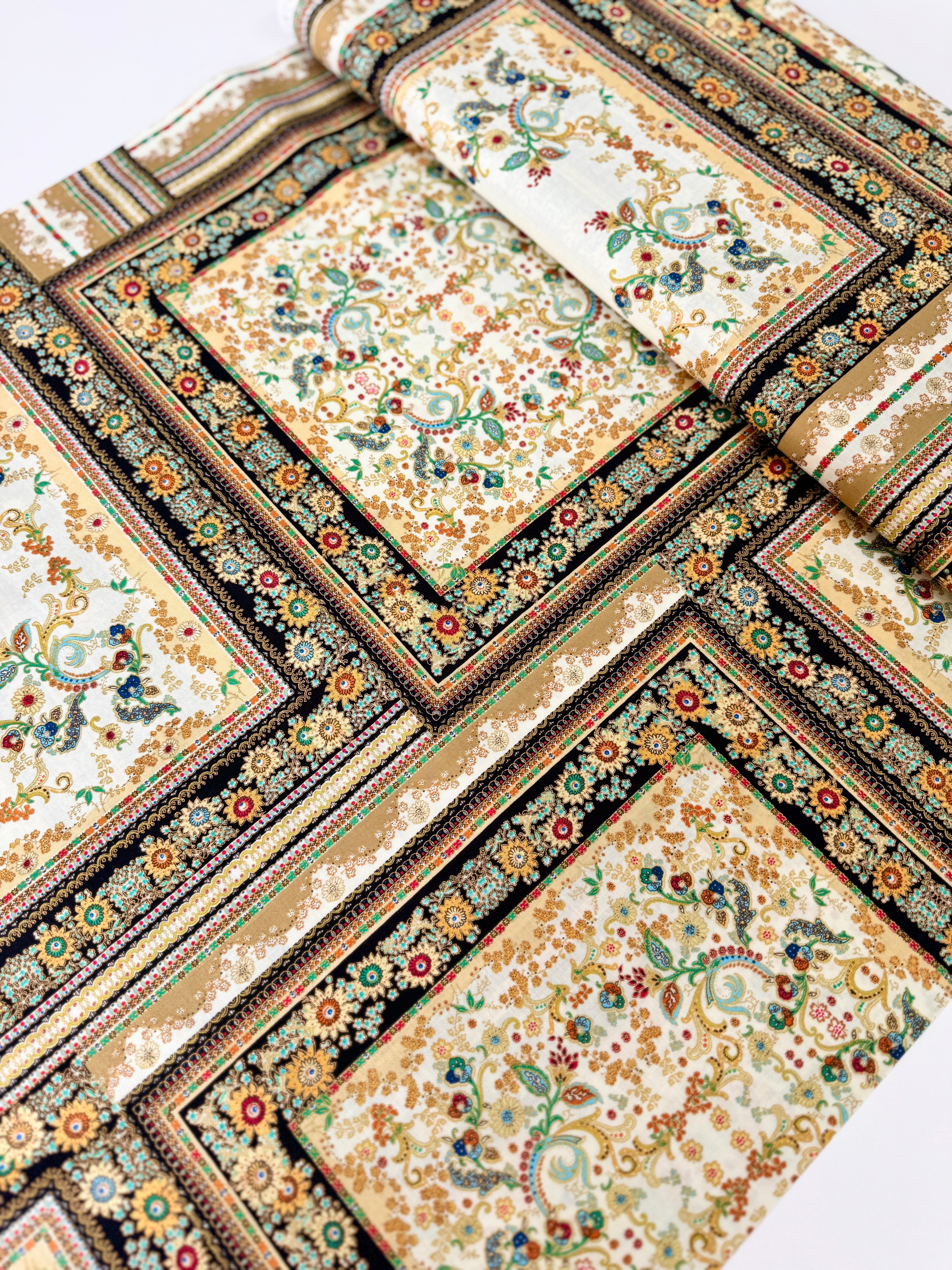 A close-up photo of Hoffman Fabrics’ Antonella Vintage Gold Metallic Fabric showing an ornate floral and scroll tapestry design in gold, cream, and black with shimmering metallic accents.