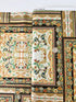 A close-up photo of Hoffman Fabrics’ Antonella Vintage Gold Metallic Fabric showing an ornate floral and scroll tapestry design in gold, cream, and black with shimmering metallic accents.