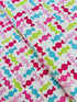 Cupcake Cafe - Wrapped Hard Candies on Pink/White Grid Fabric by Laura Stone for Studio E Fabrics featuring colorful candy motifs on a pink and white lattice background.