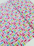 Cupcake Cafe - Wrapped Hard Candies on Pink/White Grid Fabric by Laura Stone for Studio E Fabrics featuring colorful candy motifs on a pink and white lattice background.