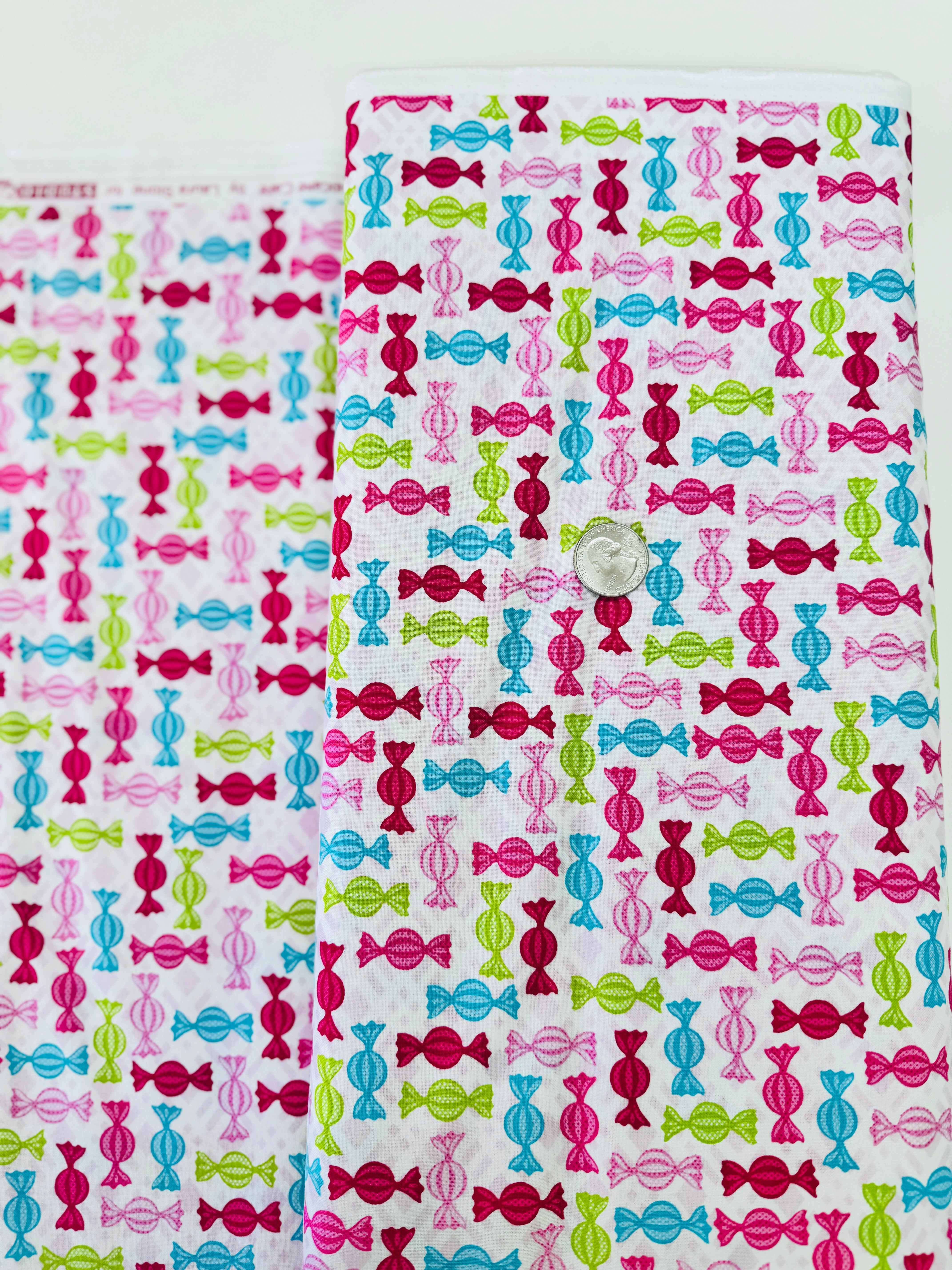 Cupcake Cafe - Wrapped Hard Candies on Pink/White Grid Fabric by Laura Stone for Studio E Fabrics featuring colorful candy motifs on a pink and white lattice background.