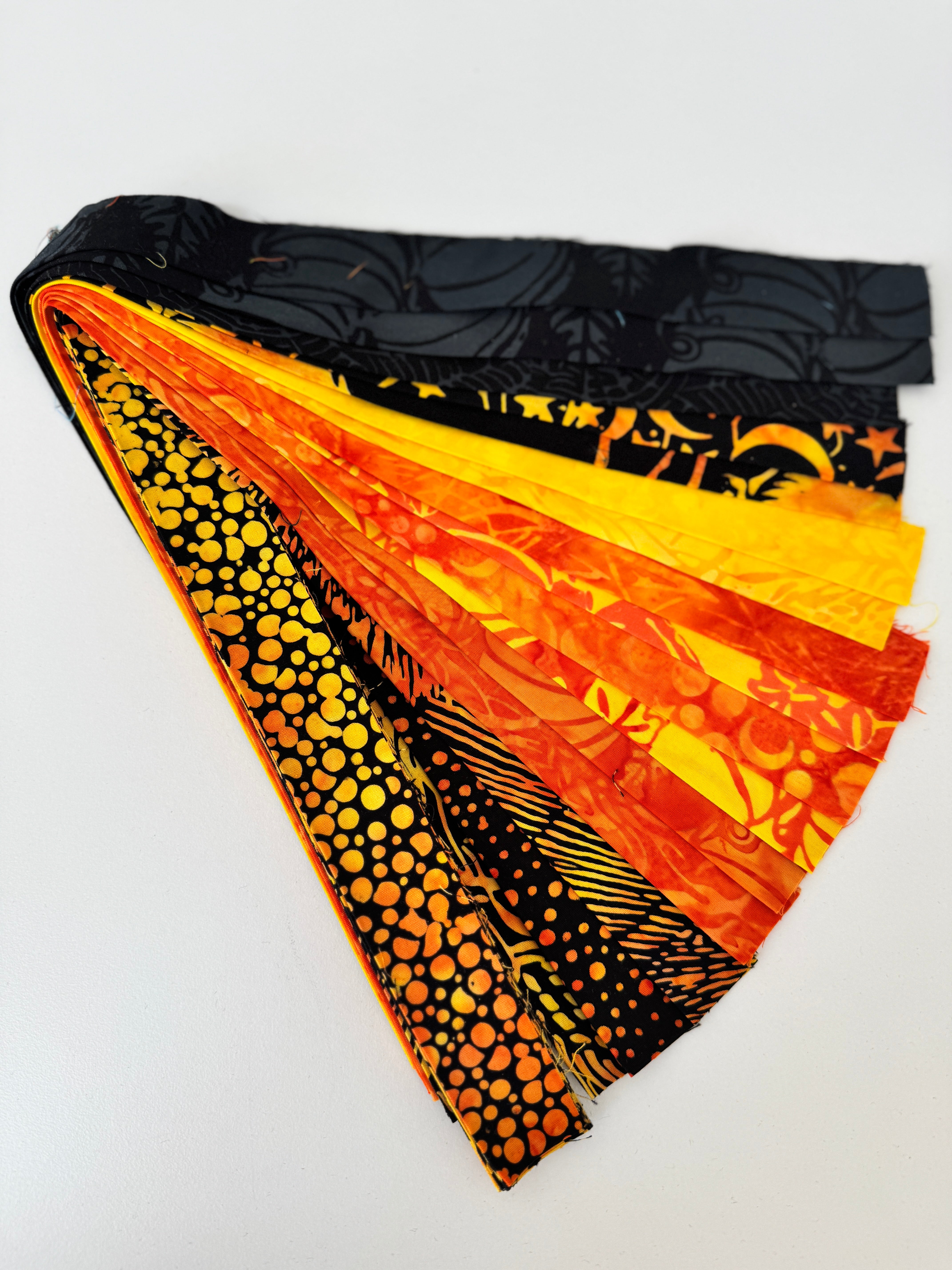 Assorted Halloween batik scrap strip bundle in orange, black, and gold tones, 2-inch strips by Island Batik.