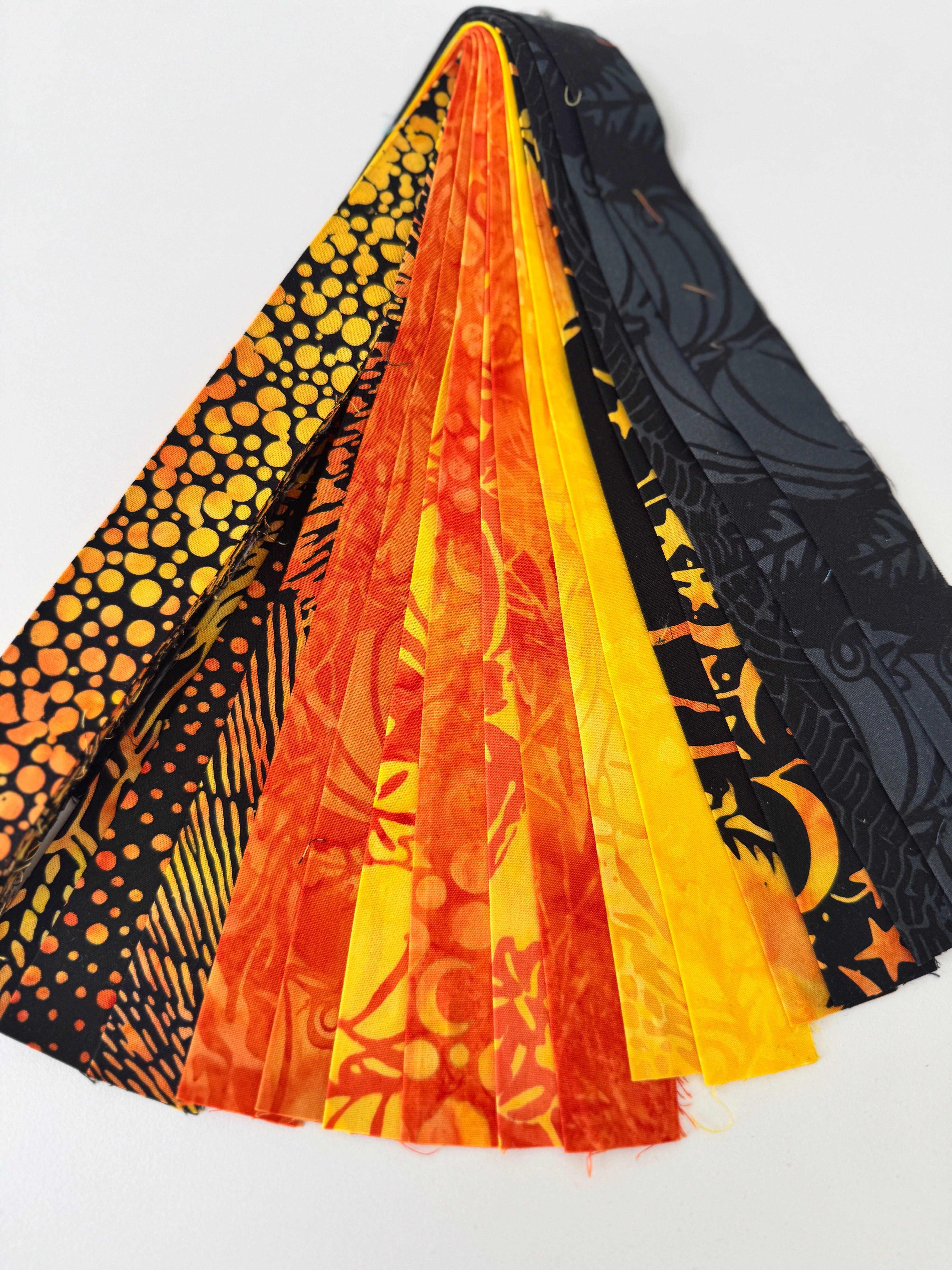 Assorted Halloween batik scrap strip bundle in orange, black, and gold tones, 2-inch strips by Island Batik.
