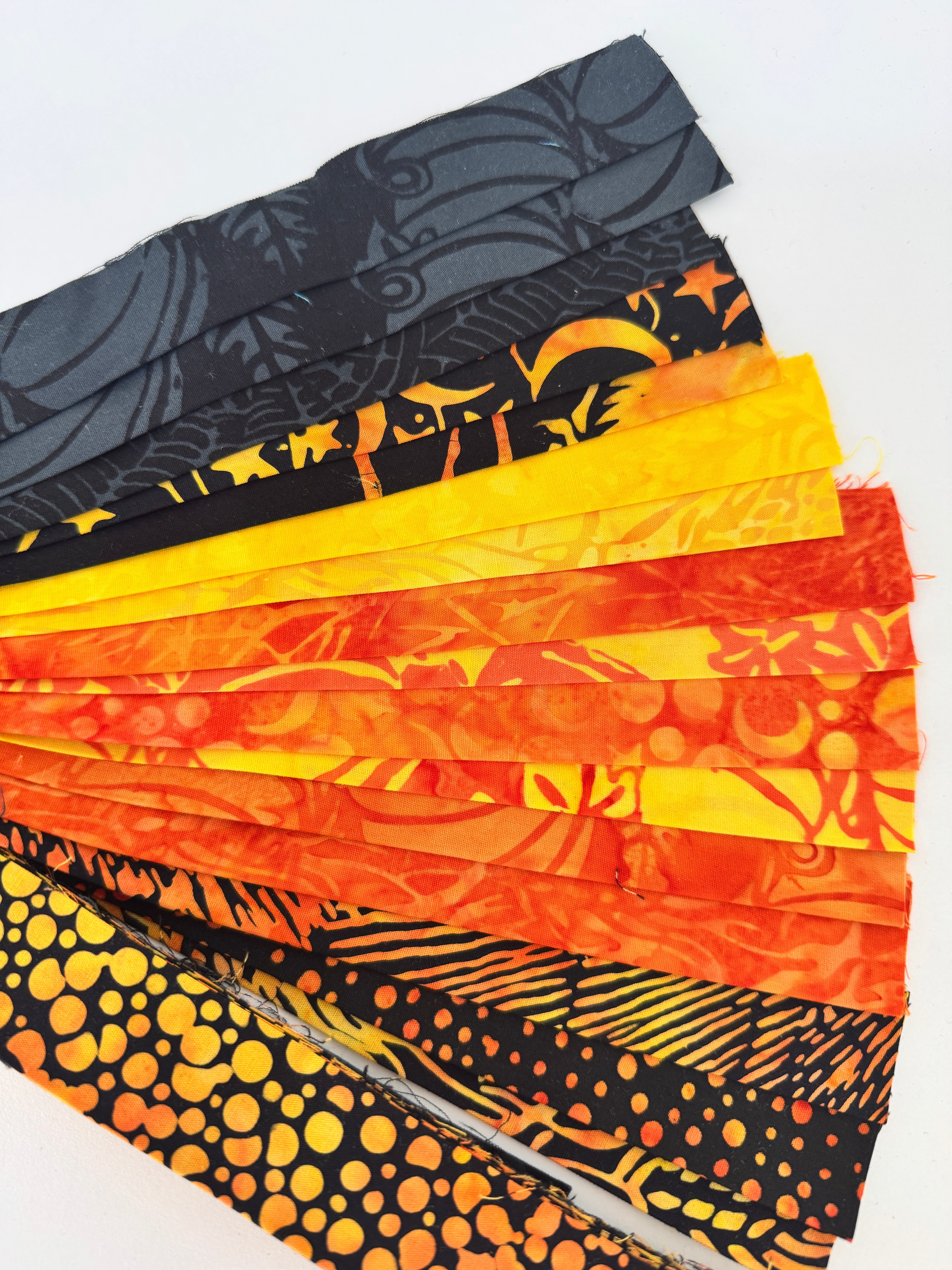 Assorted Halloween batik scrap strip bundle in orange, black, and gold tones, 2-inch strips by Island Batik.