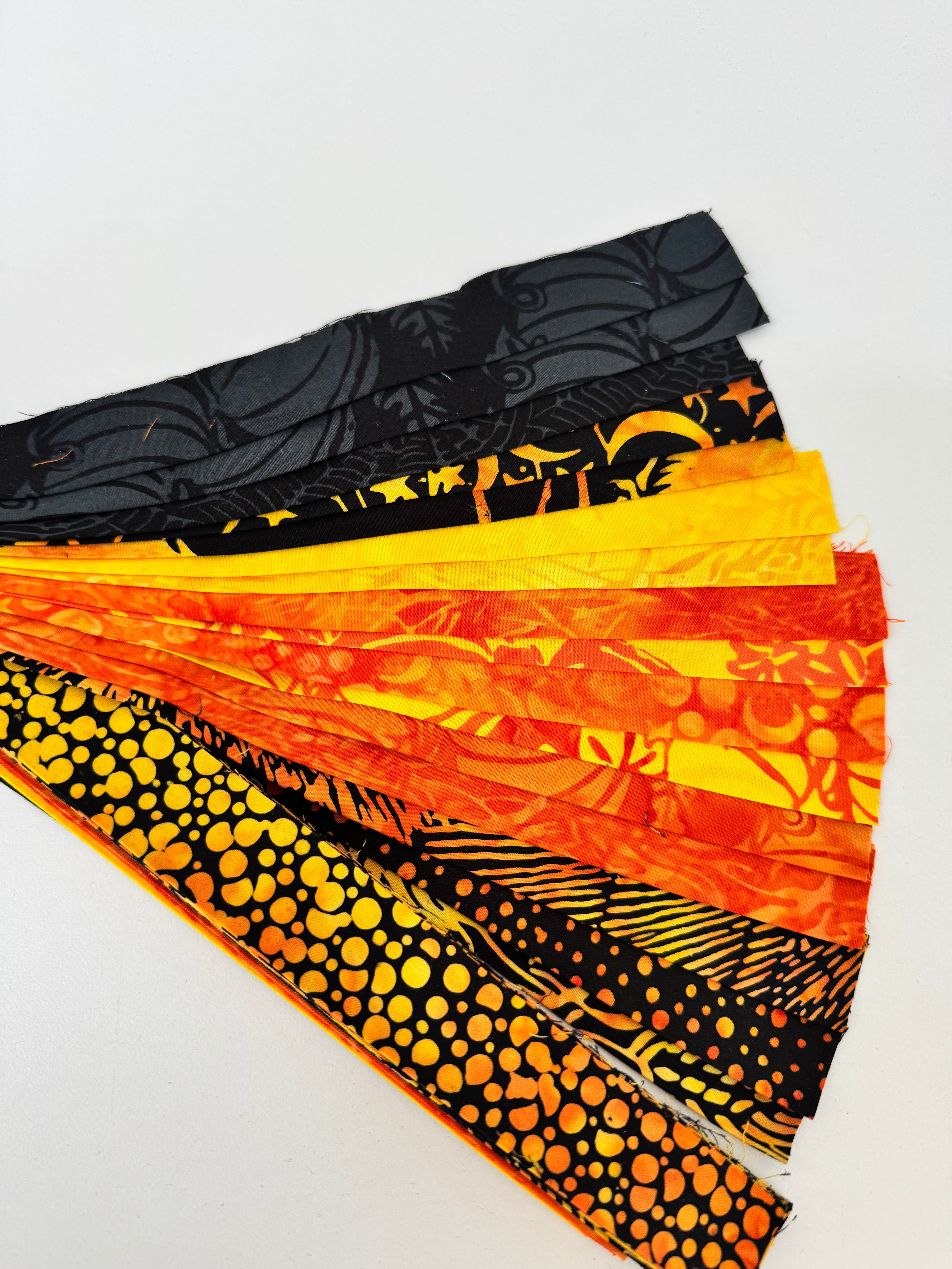 Assorted Halloween batik scrap strip bundle in orange, black, and gold tones, 2-inch strips by Island Batik.