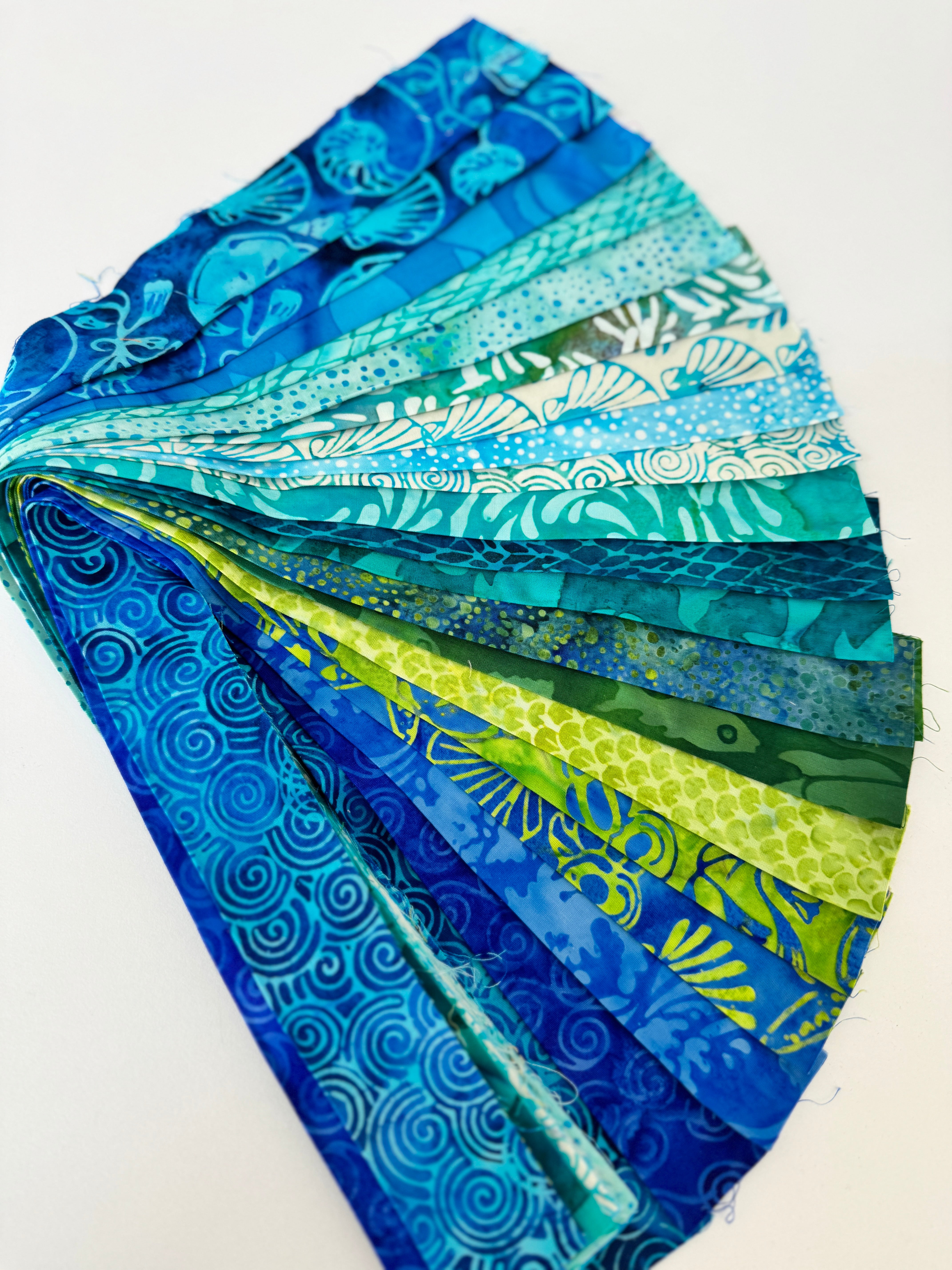 Assorted ocean-themed batik scrap strip bundle in blue, teal, and green 2-inch strips by Island Batik.