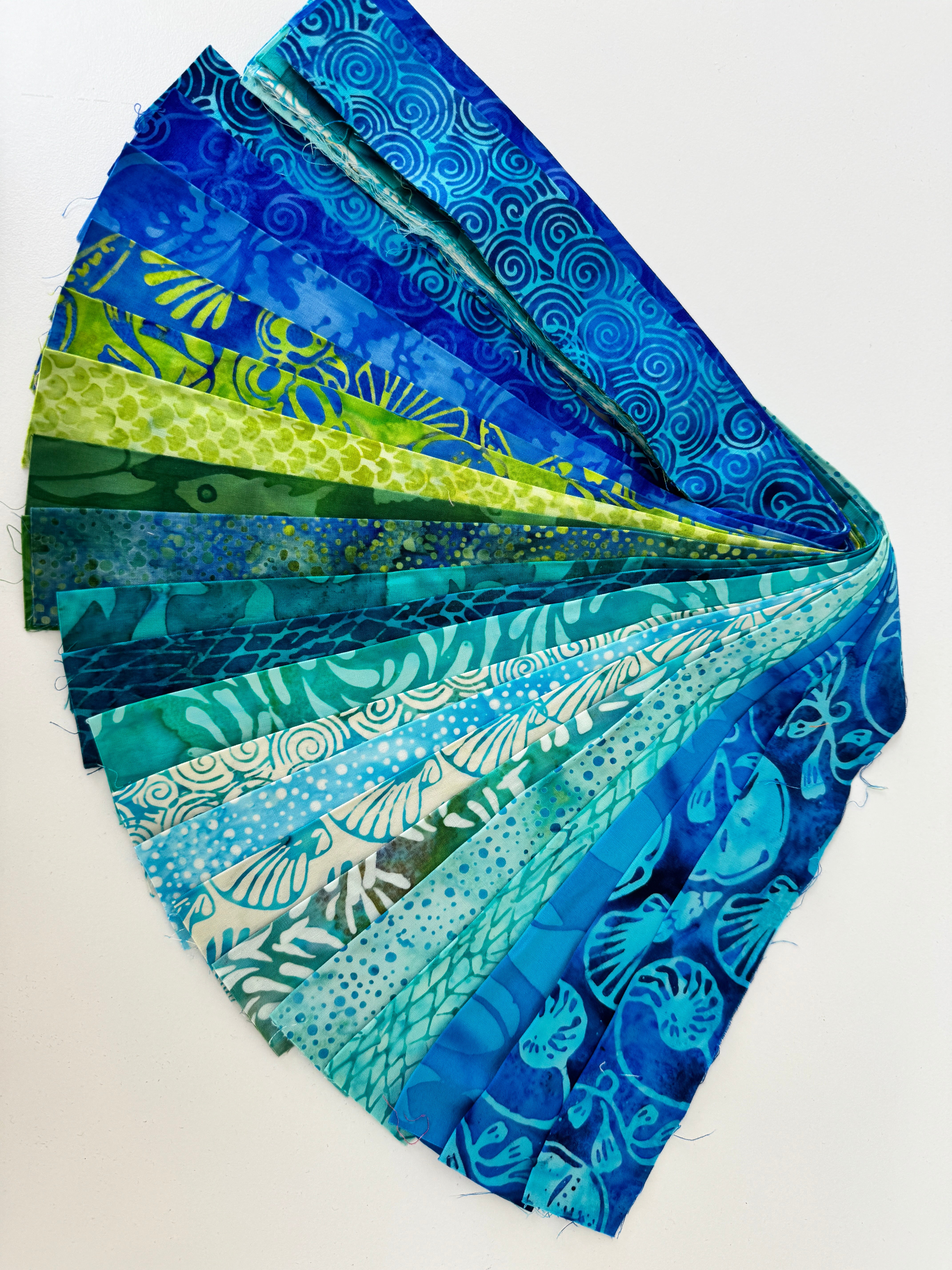 Assorted ocean-themed batik scrap strip bundle in blue, teal, and green 2-inch strips by Island Batik.
