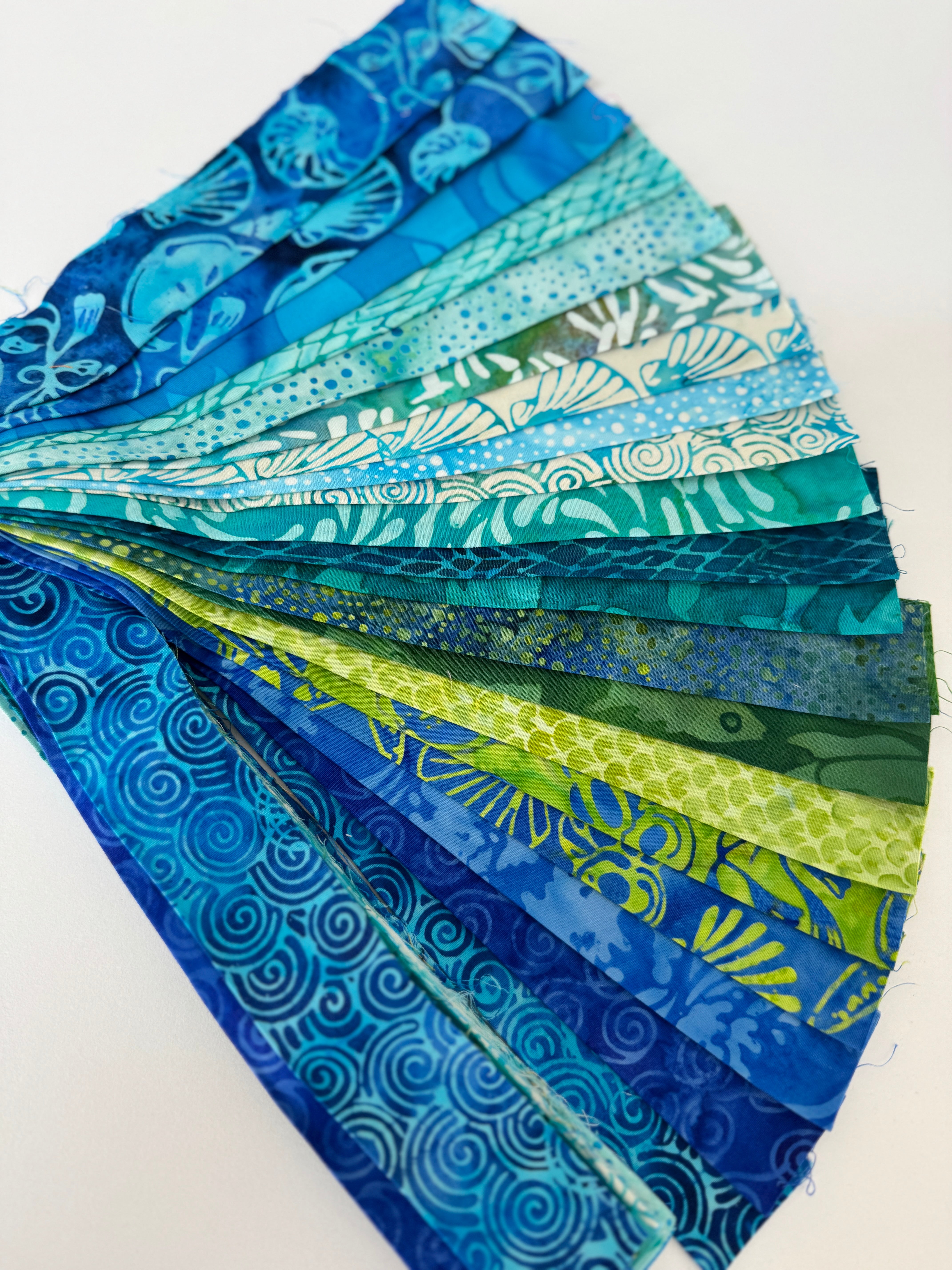 Assorted ocean-themed batik scrap strip bundle in blue, teal, and green 2-inch strips by Island Batik.