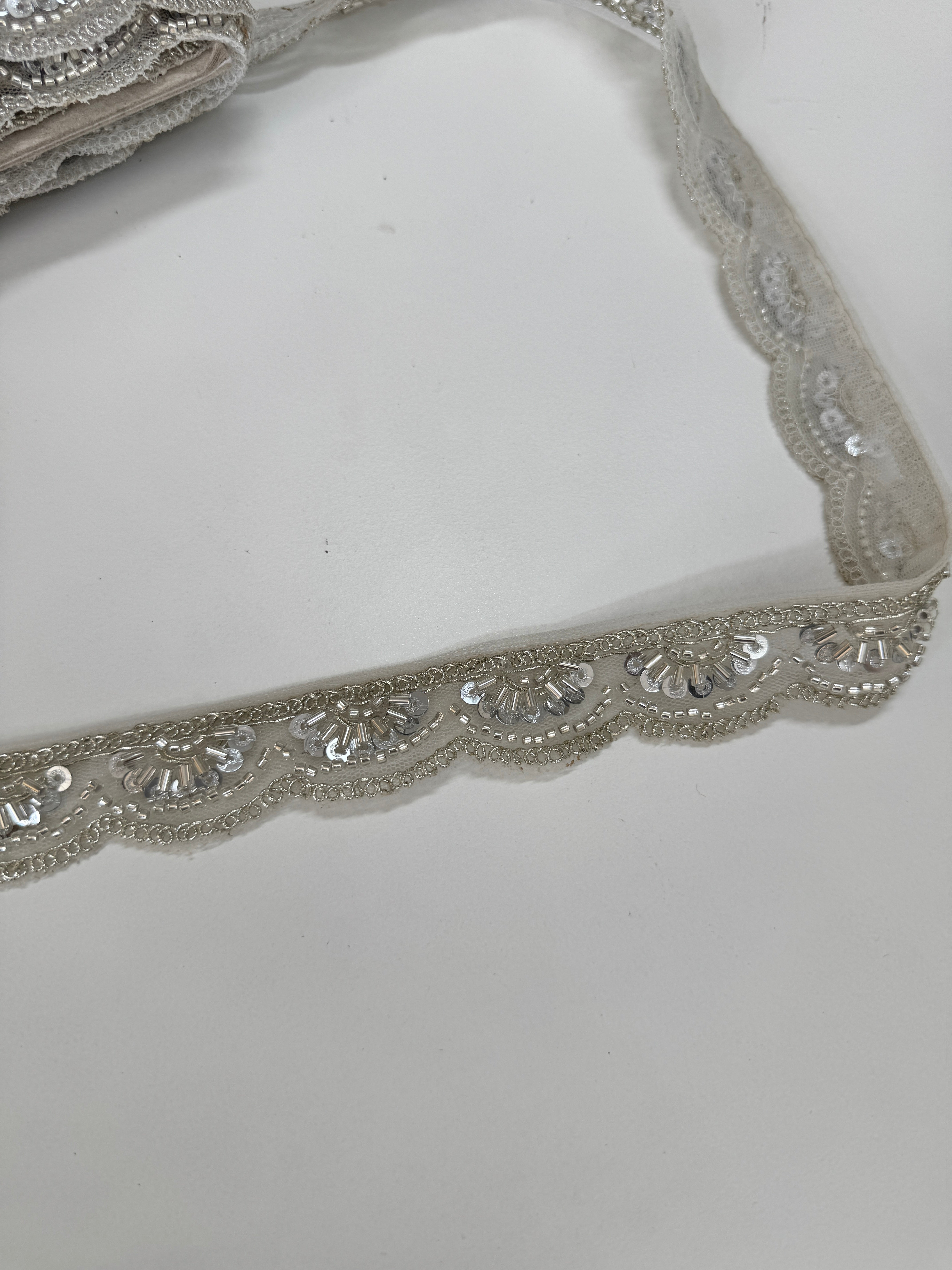 Silver beaded lace trim with sequins, embroidery, and scalloped edge for bridal gowns, veils, lehengas, sarees, couture garments, and sewing projects.