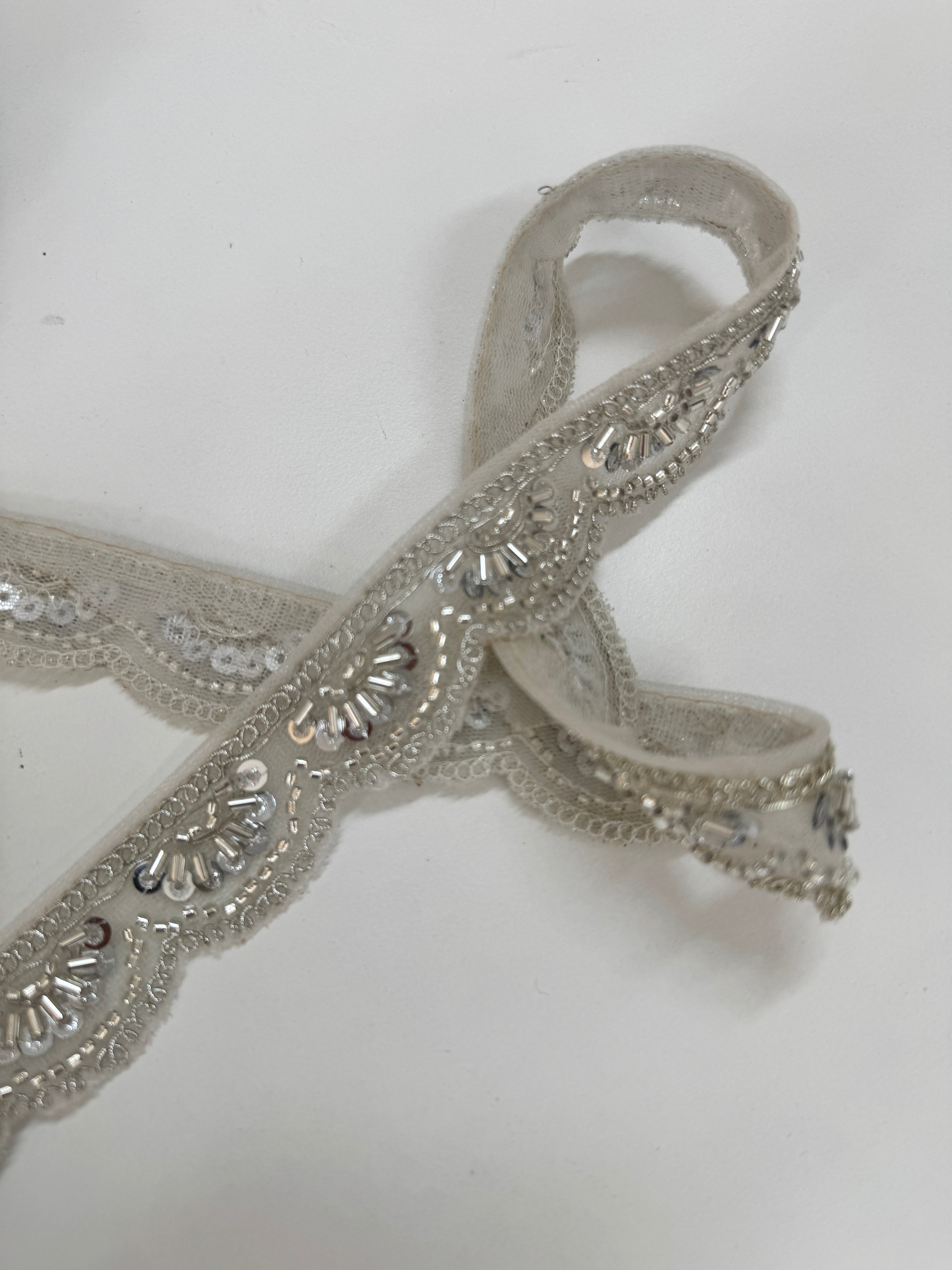 Silver beaded lace trim with sequins, embroidery, and scalloped edge for bridal gowns, veils, lehengas, sarees, couture garments, and sewing projects.