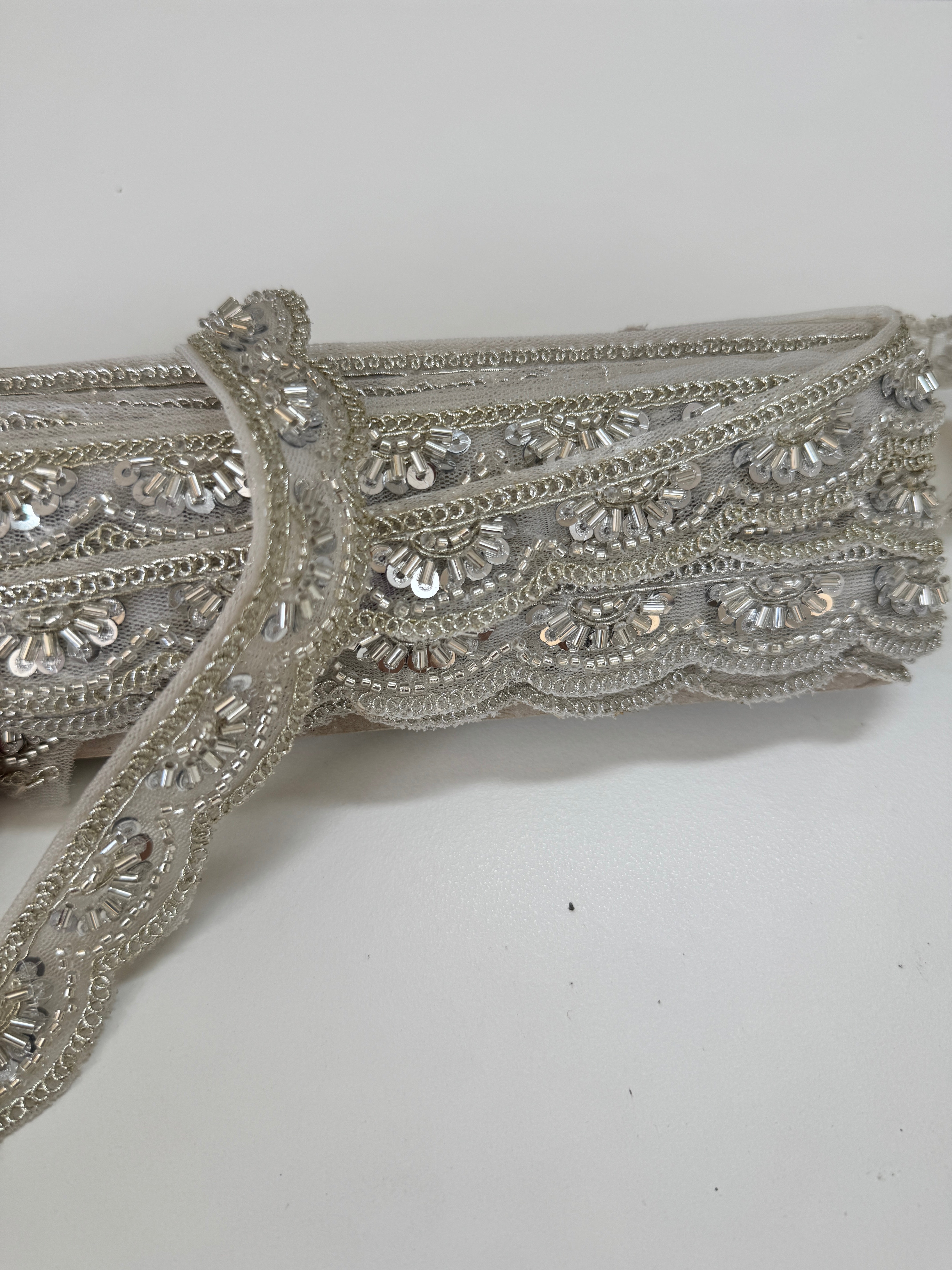 Silver beaded lace trim with sequins, embroidery, and scalloped edge for bridal gowns, veils, lehengas, sarees, couture garments, and sewing projects.