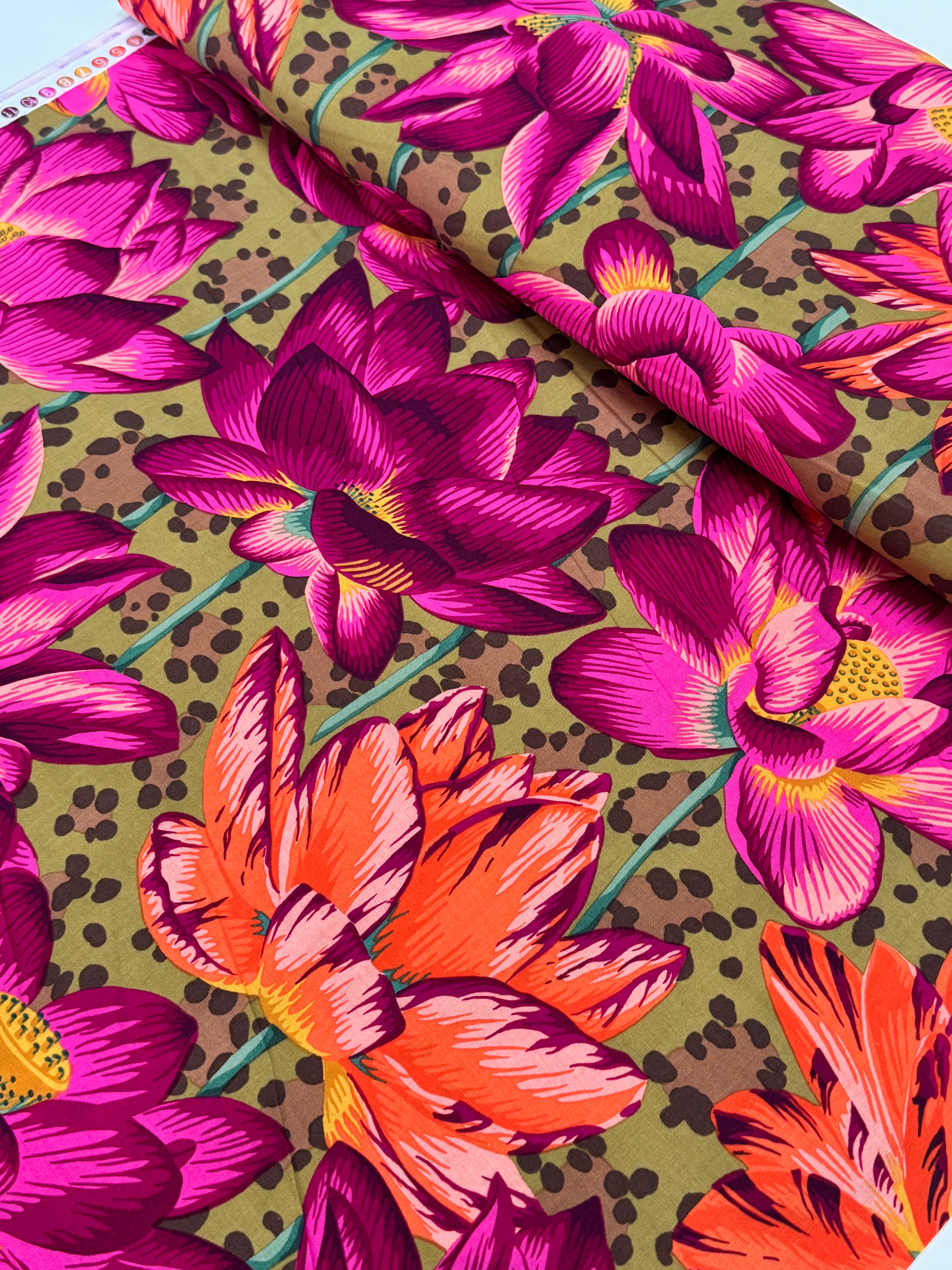 Large pink, magenta, and coral lotus flowers on an ochre leopard-print background, Leopard Lotus Ochre fabric by Philip Jacobs for FreeSpirit Fabrics.