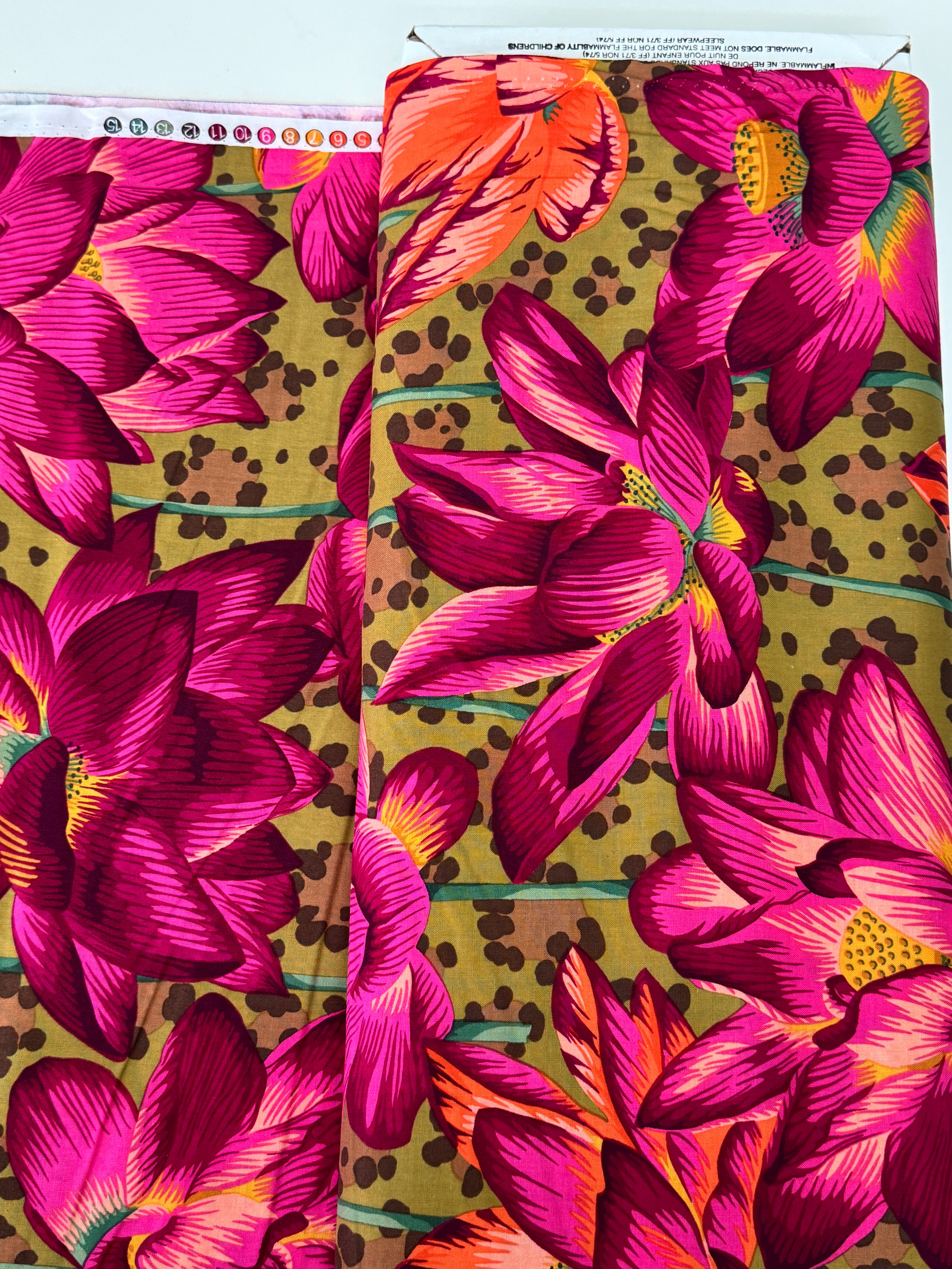 Large pink, magenta, and coral lotus flowers on an ochre leopard-print background, Leopard Lotus Ochre fabric by Philip Jacobs for FreeSpirit Fabrics.