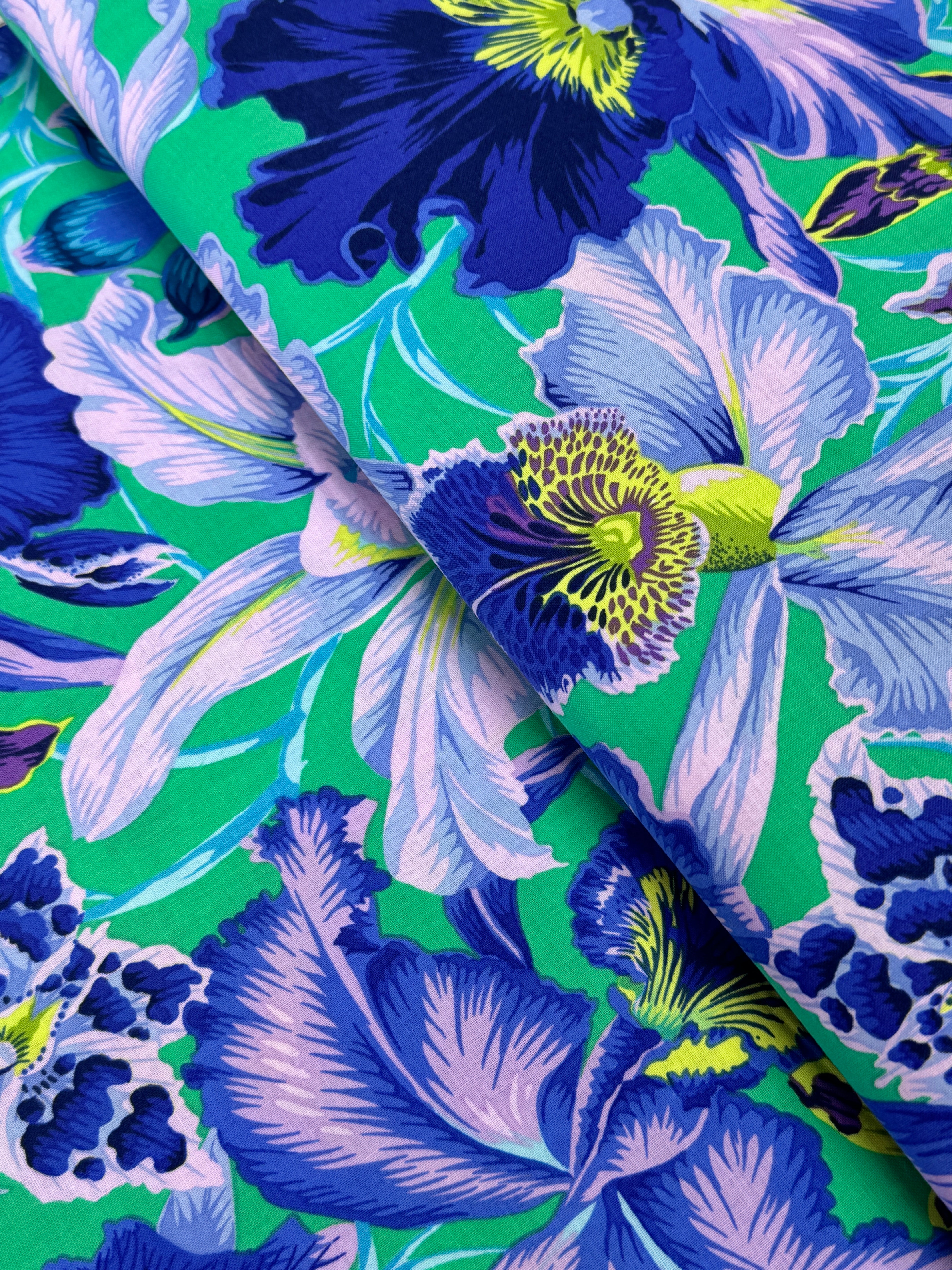 Large blue and lavender orchids with tropical blooms on a vibrant turquoise background, Orchids Blue fabric by Philip Jacobs for FreeSpirit Fabrics.