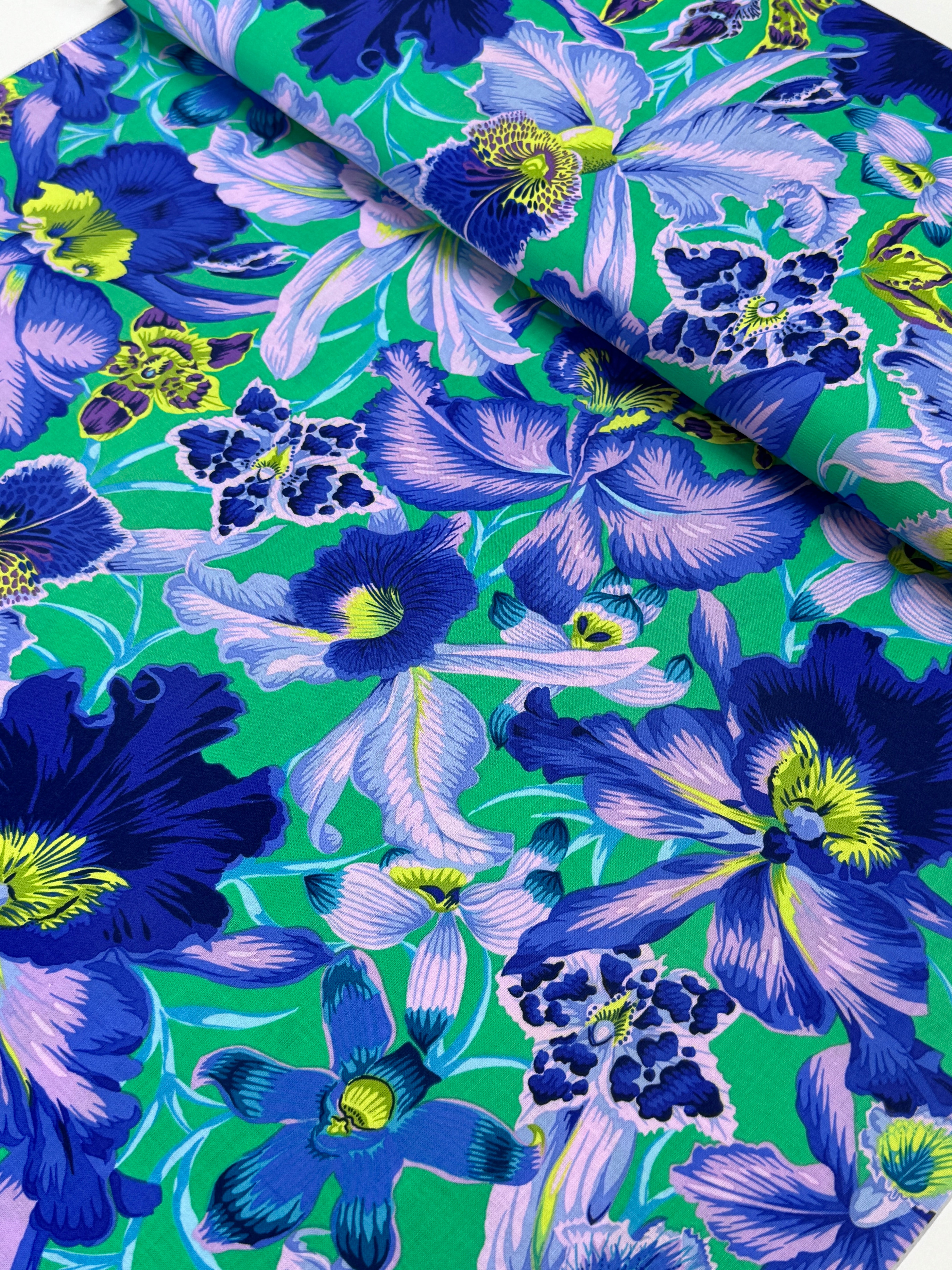 Large blue and lavender orchids with tropical blooms on a vibrant turquoise background, Orchids Blue fabric by Philip Jacobs for FreeSpirit Fabrics.