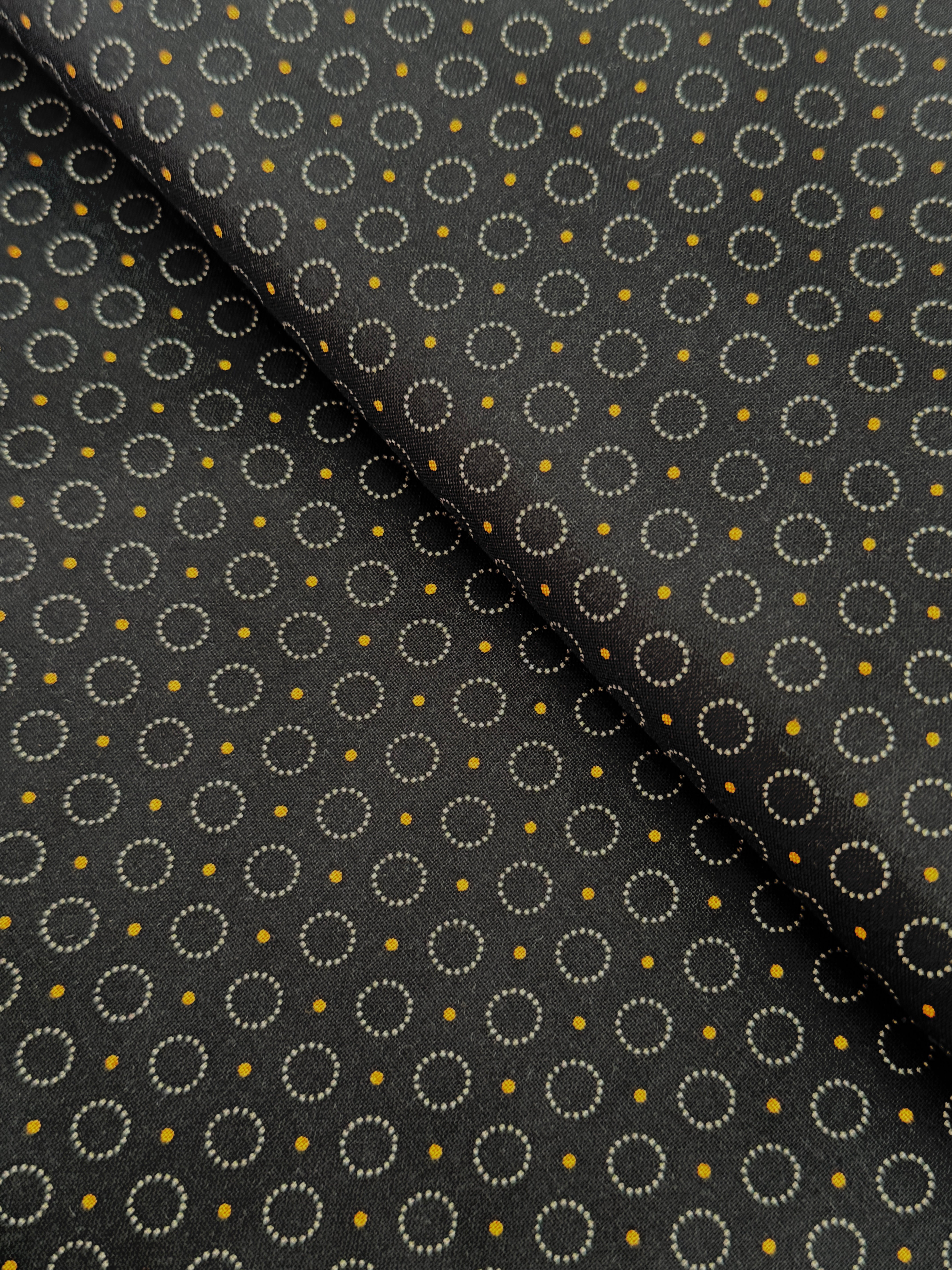 Gray stitched circles and tiny golden dots scattered across a black background, Rings of Dots Black fabric from the Harvest Moon collection by Andover Fabrics.