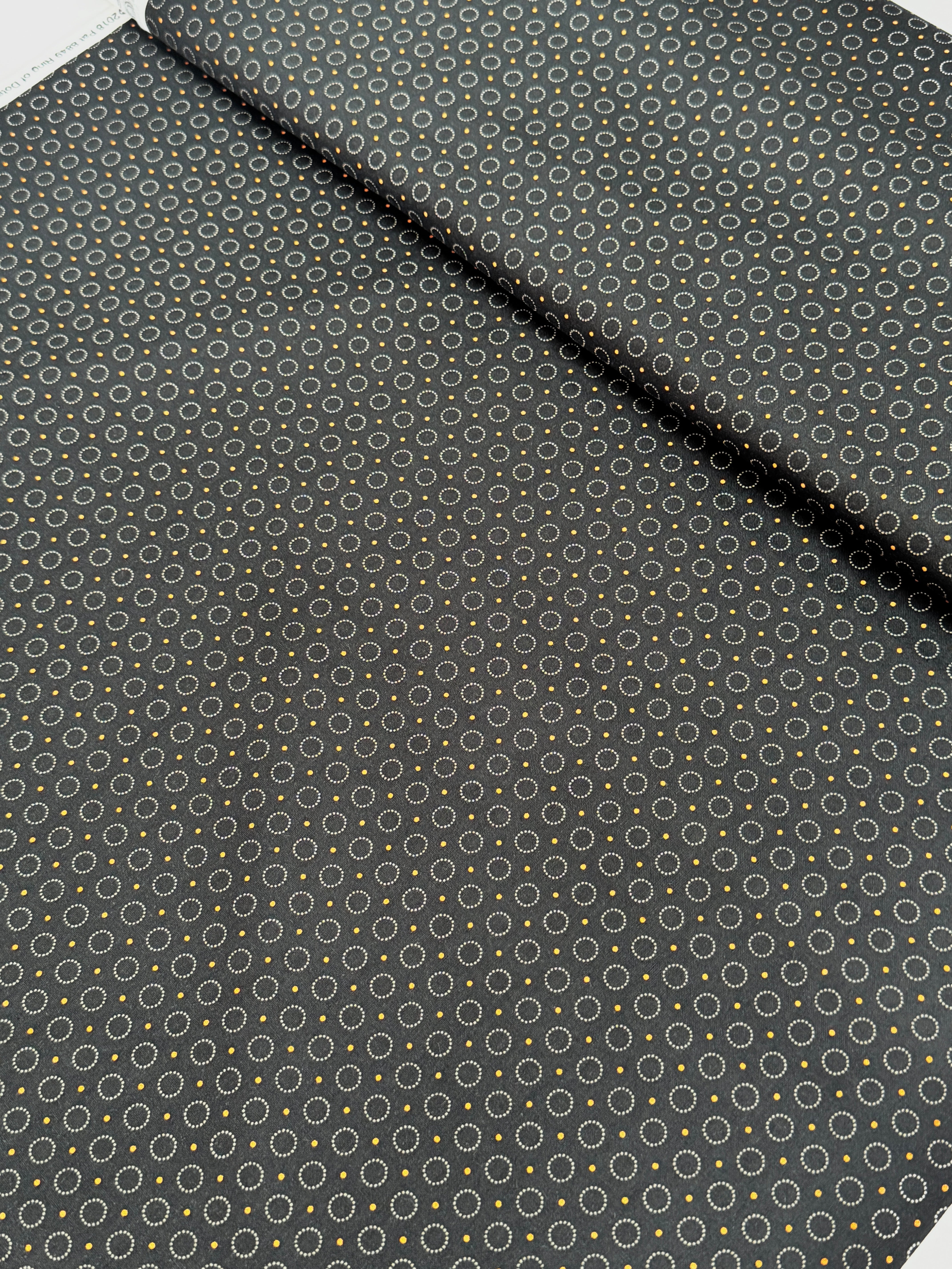 Gray stitched circles and tiny golden dots scattered across a black background, Rings of Dots Black fabric from the Harvest Moon collection by Andover Fabrics.