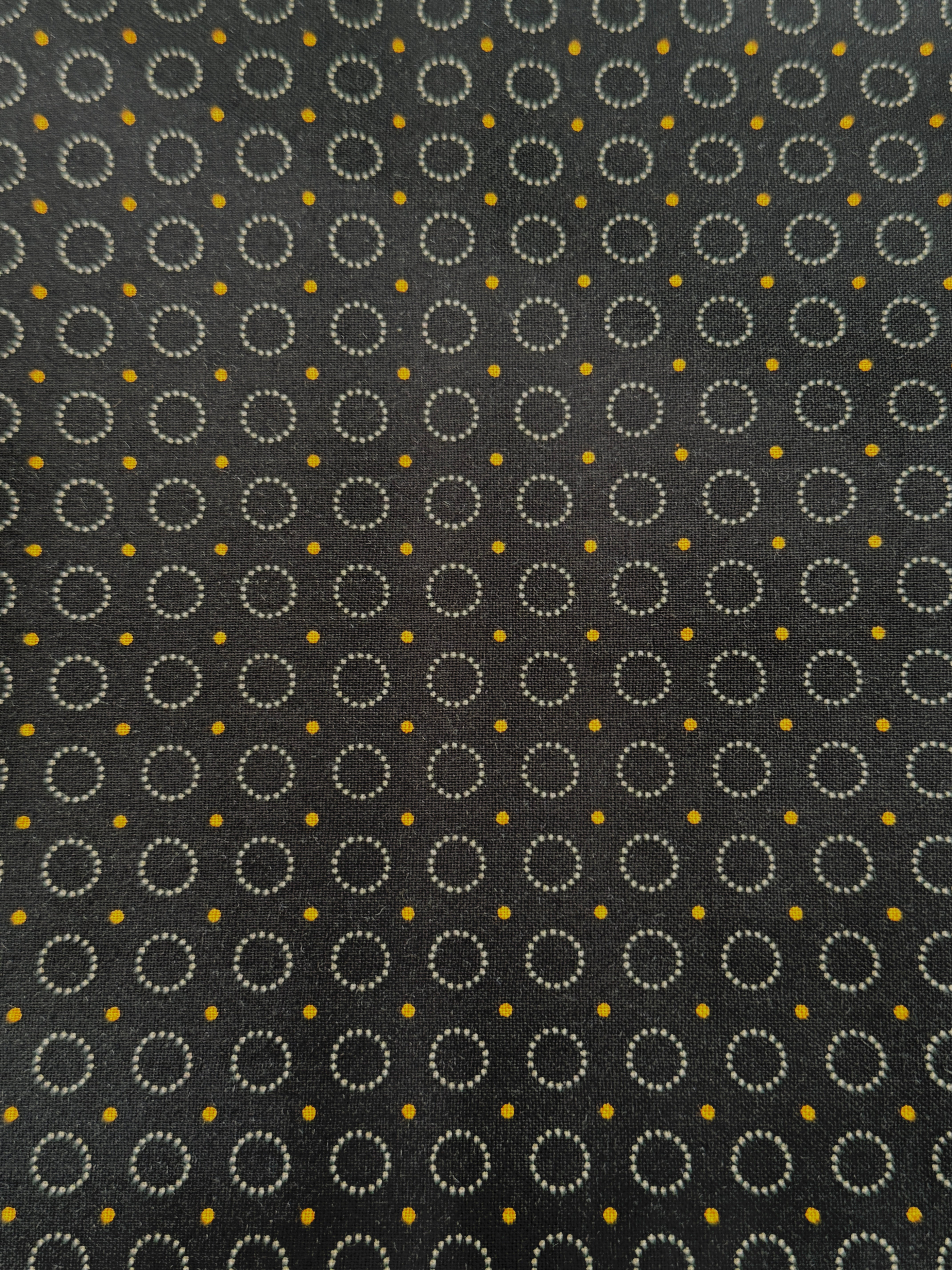 Gray stitched circles and tiny golden dots scattered across a black background, Rings of Dots Black fabric from the Harvest Moon collection by Andover Fabrics.