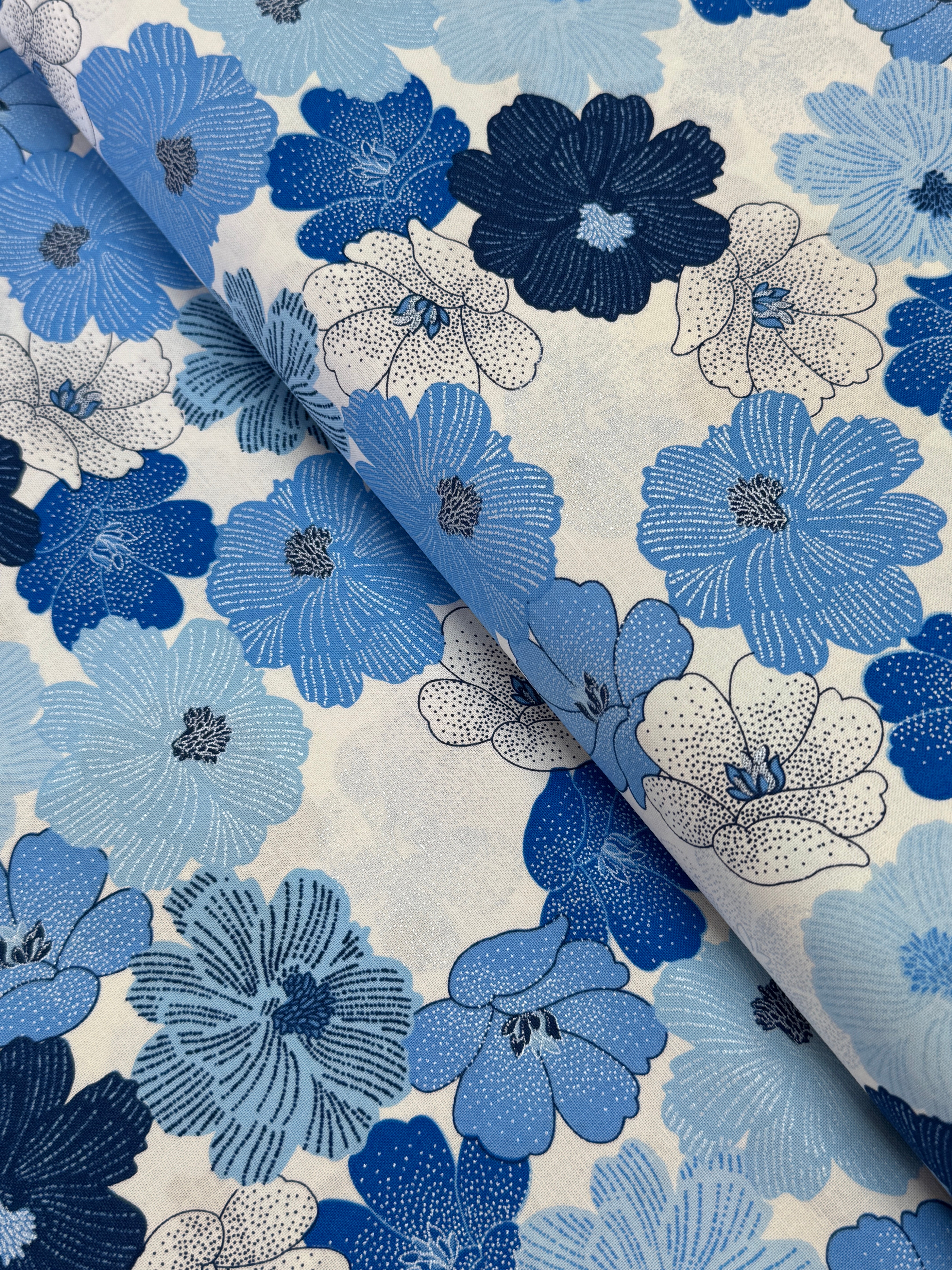 Blue and white flowers with pearlescent shimmer accents scattered across a white background, Packed Shimmer Flower White Pearlescent fabric by Greta Lynn for Kanvas Studio Benartex.