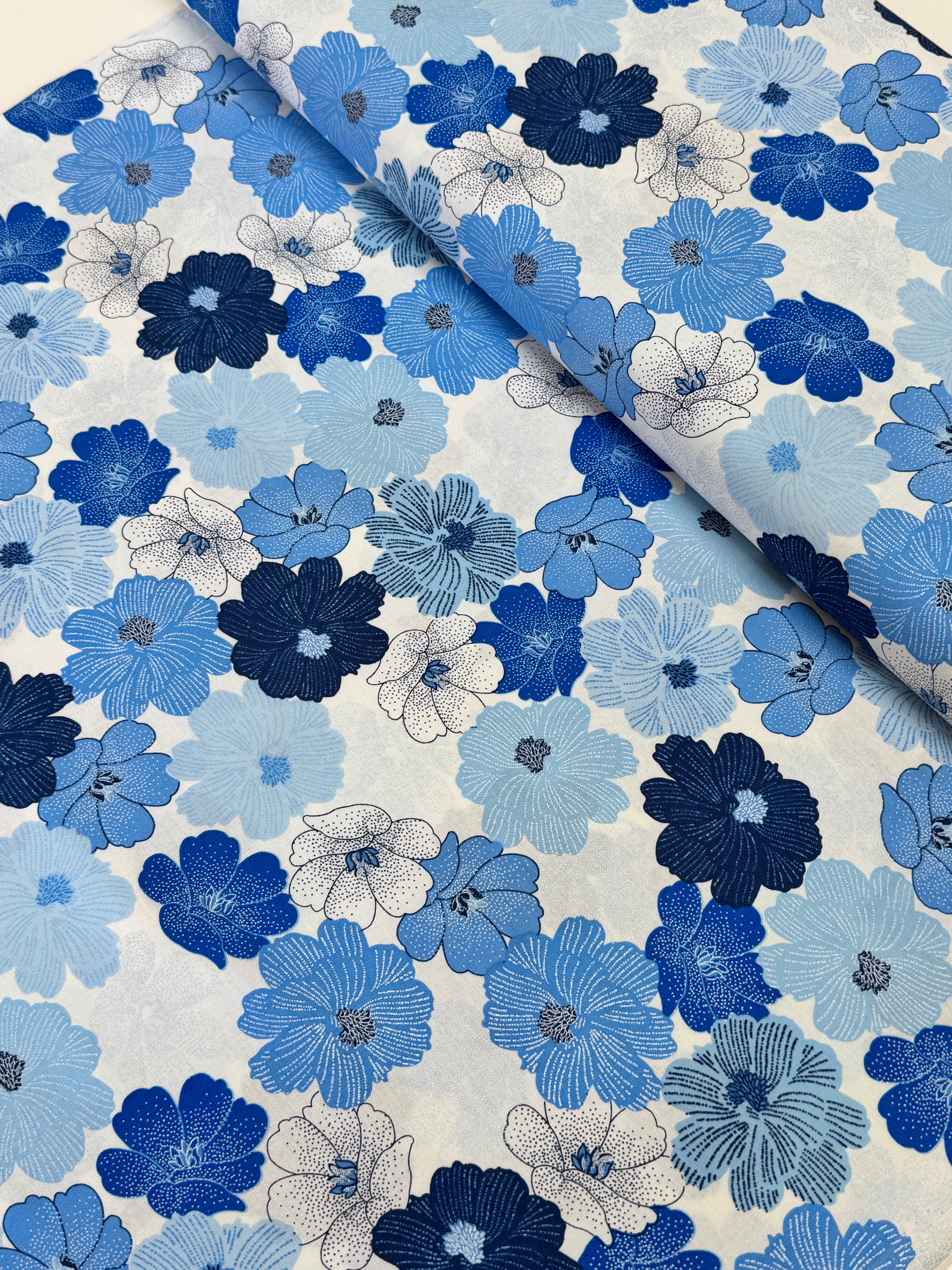 Blue and white flowers with pearlescent shimmer accents scattered across a white background, Packed Shimmer Flower White Pearlescent fabric by Greta Lynn for Kanvas Studio Benartex.