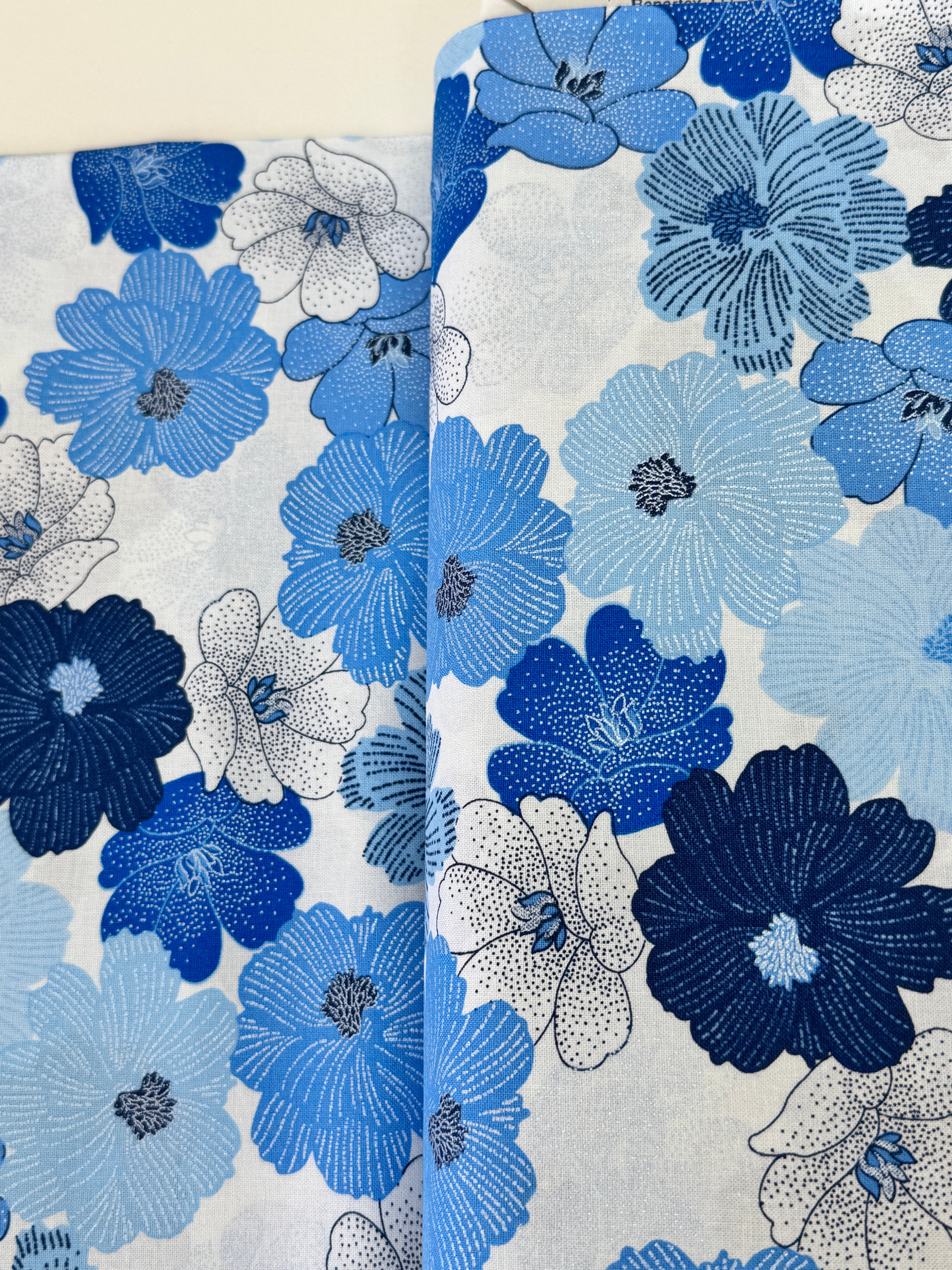 Blue and white flowers with pearlescent shimmer accents scattered across a white background, Packed Shimmer Flower White Pearlescent fabric by Greta Lynn for Kanvas Studio Benartex.